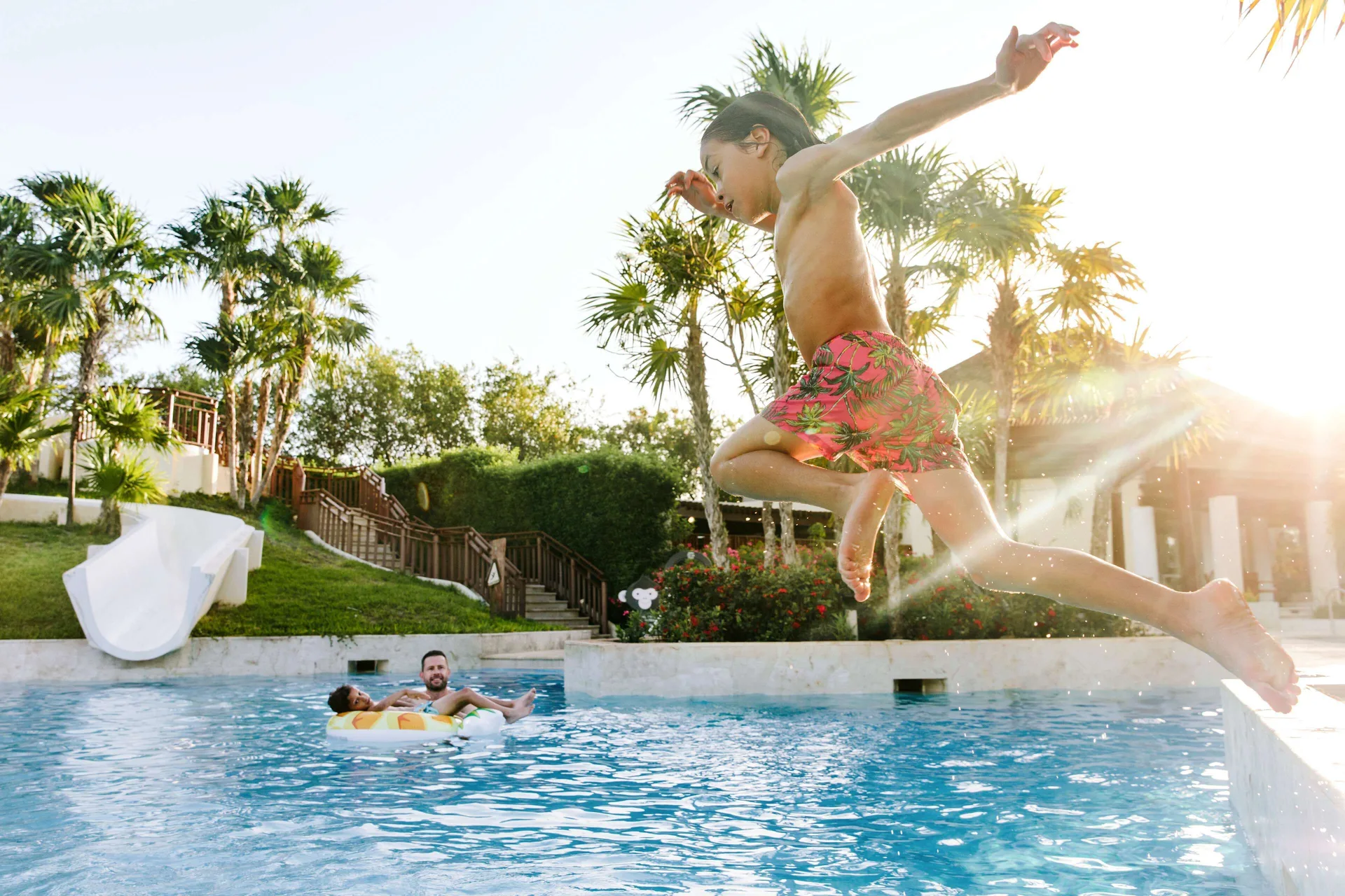 Child jumping into a pool while family floats nearby at Fairmont Mayakoba.