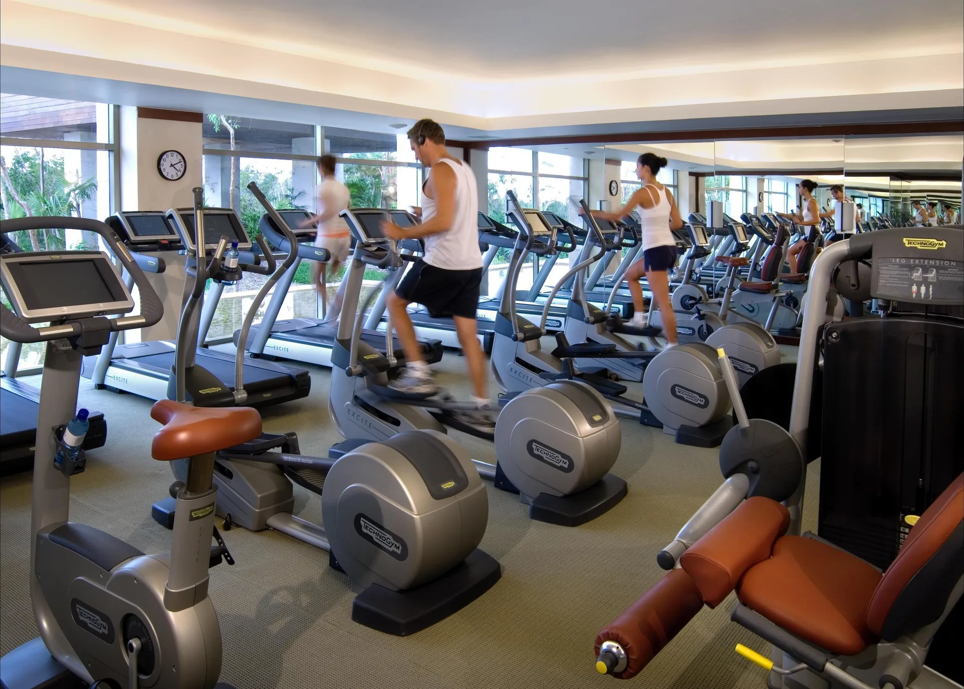 Fitness center with treadmills, bikes, strength equipment, and guests at Fairmont Mayakoba.
