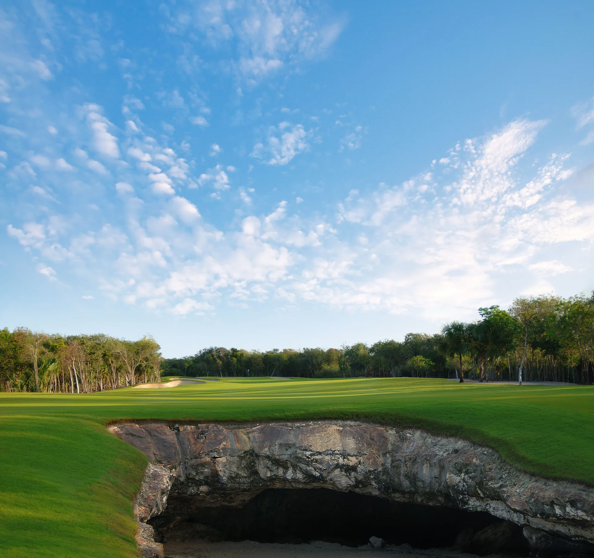 Golf fairway with a rocky cave feature at Fairmont Mayakoba.