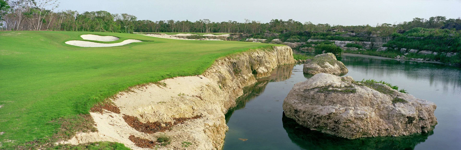 Golf fairway with sand bunkers and rocky water feature at Fairmont Mayakoba.