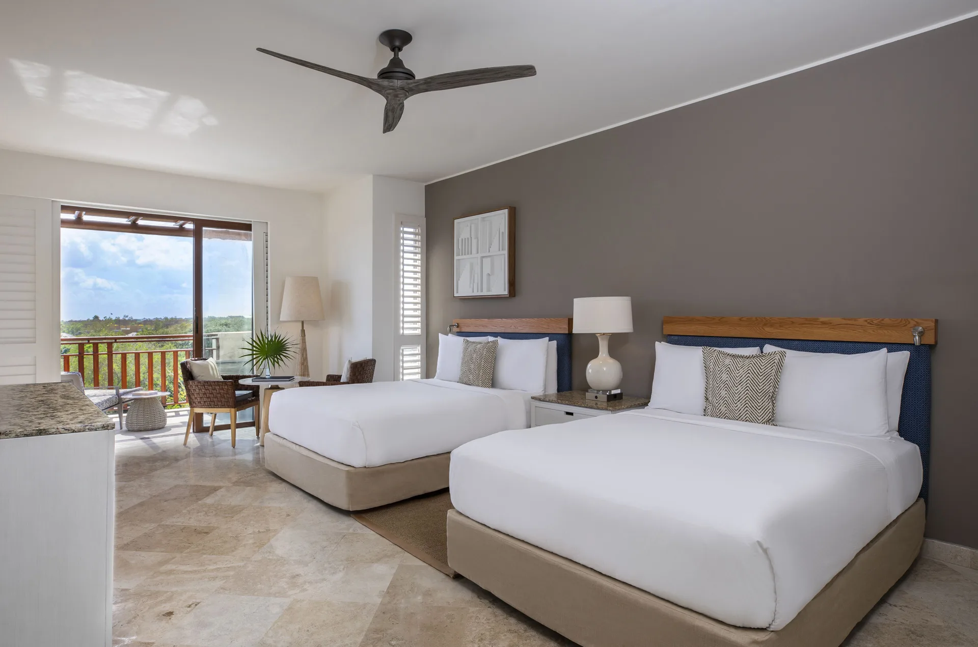 Guest room with two queen beds, seating, and balcony doors at Fairmont Mayakoba.