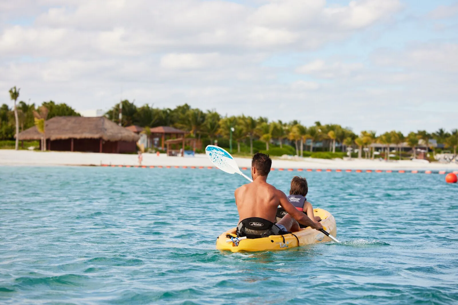 Adult and child kayaking on turquoise water near the beach at Fairmont Mayakoba.
