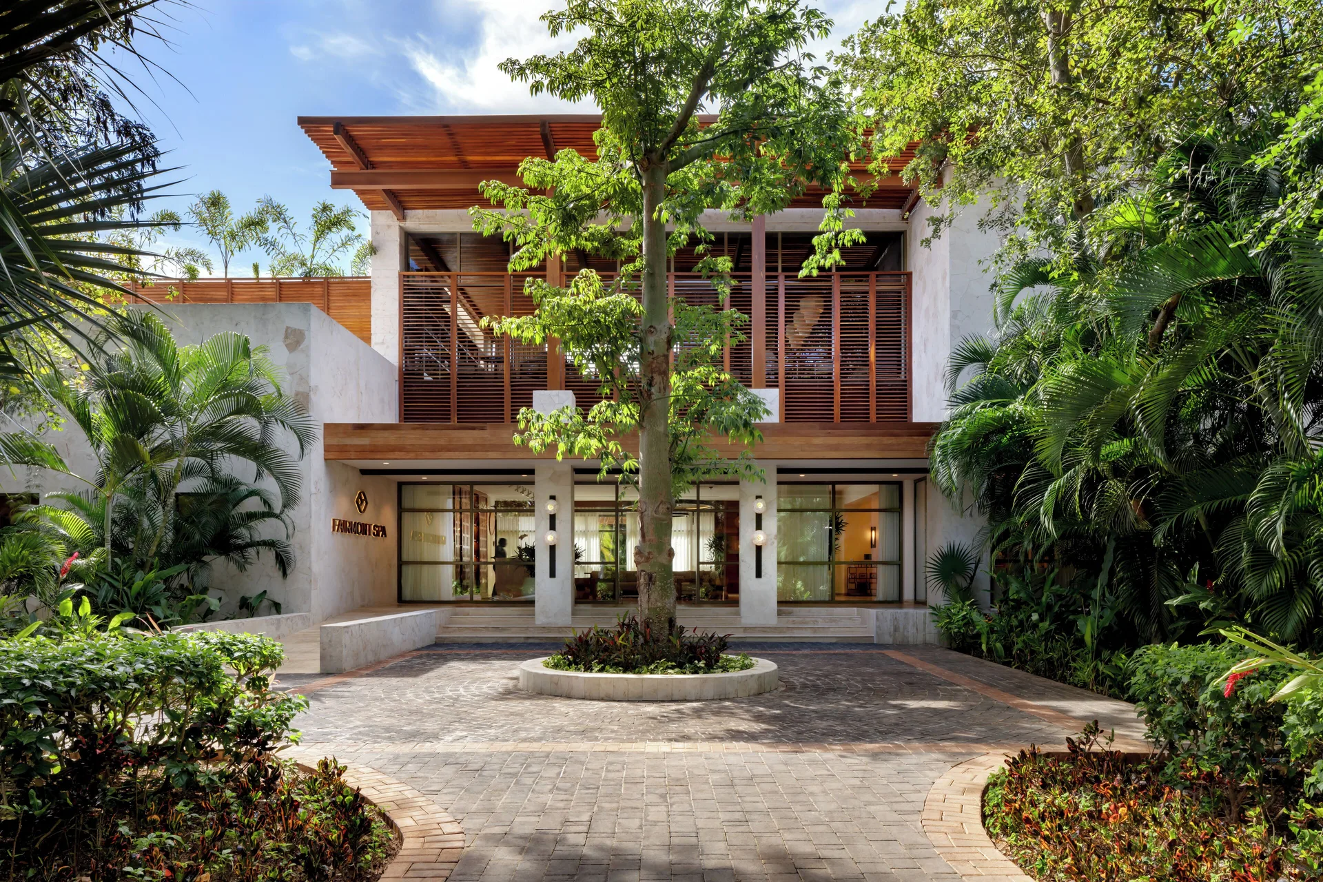 Spa entrance framed by palms and a central tree at Fairmont Mayakoba.