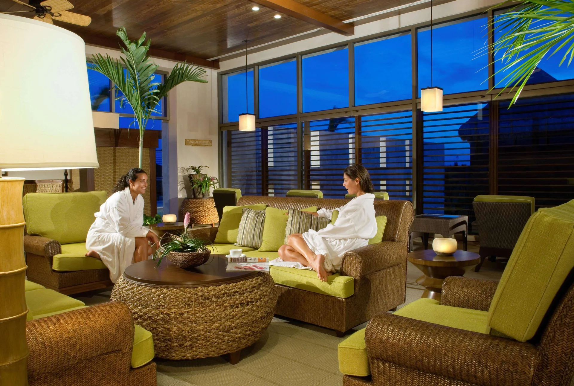Spa lounge with wicker seating and guests in robes at Fairmont Mayakoba.