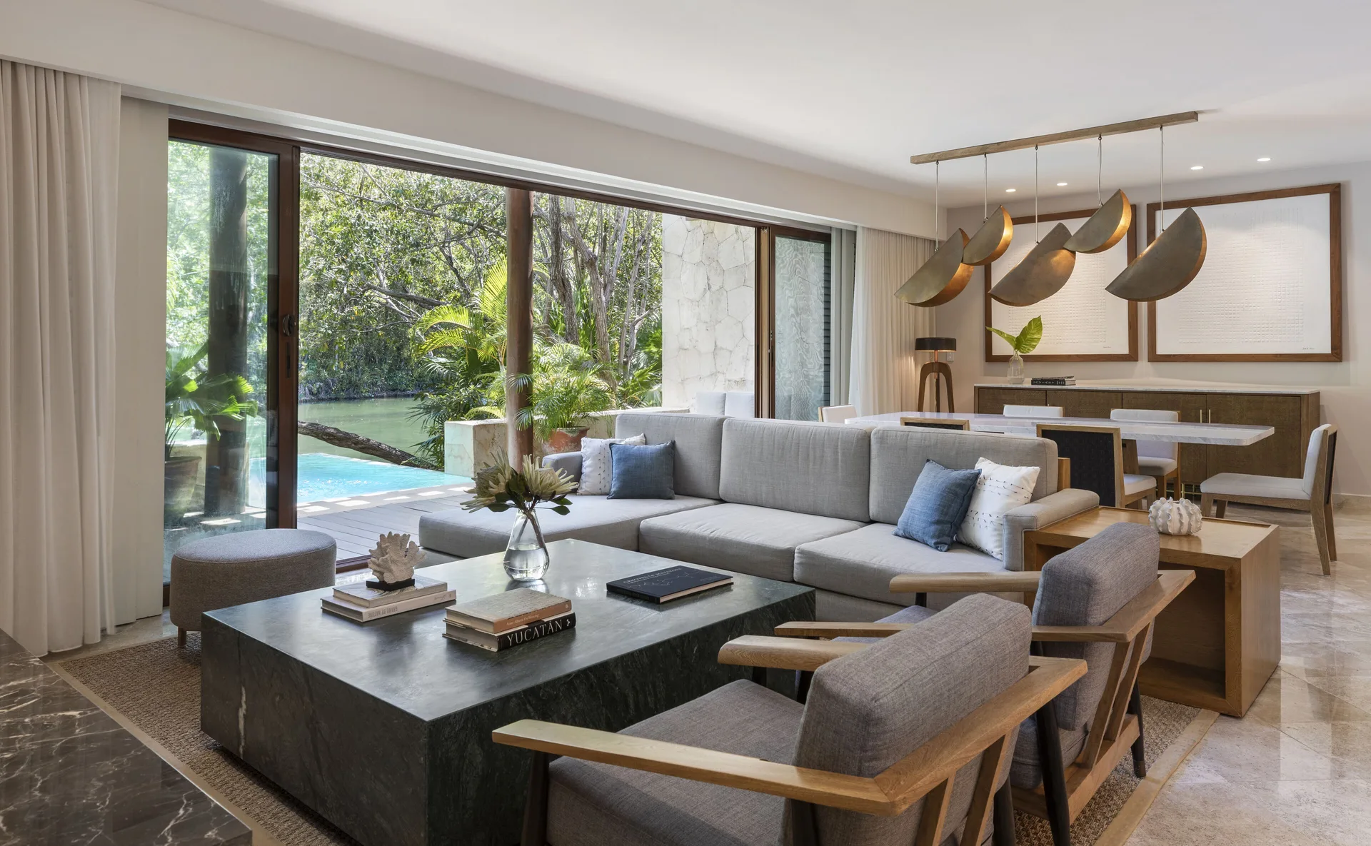 Suite living and dining room with terrace pool and lagoon view at Fairmont Mayakoba.