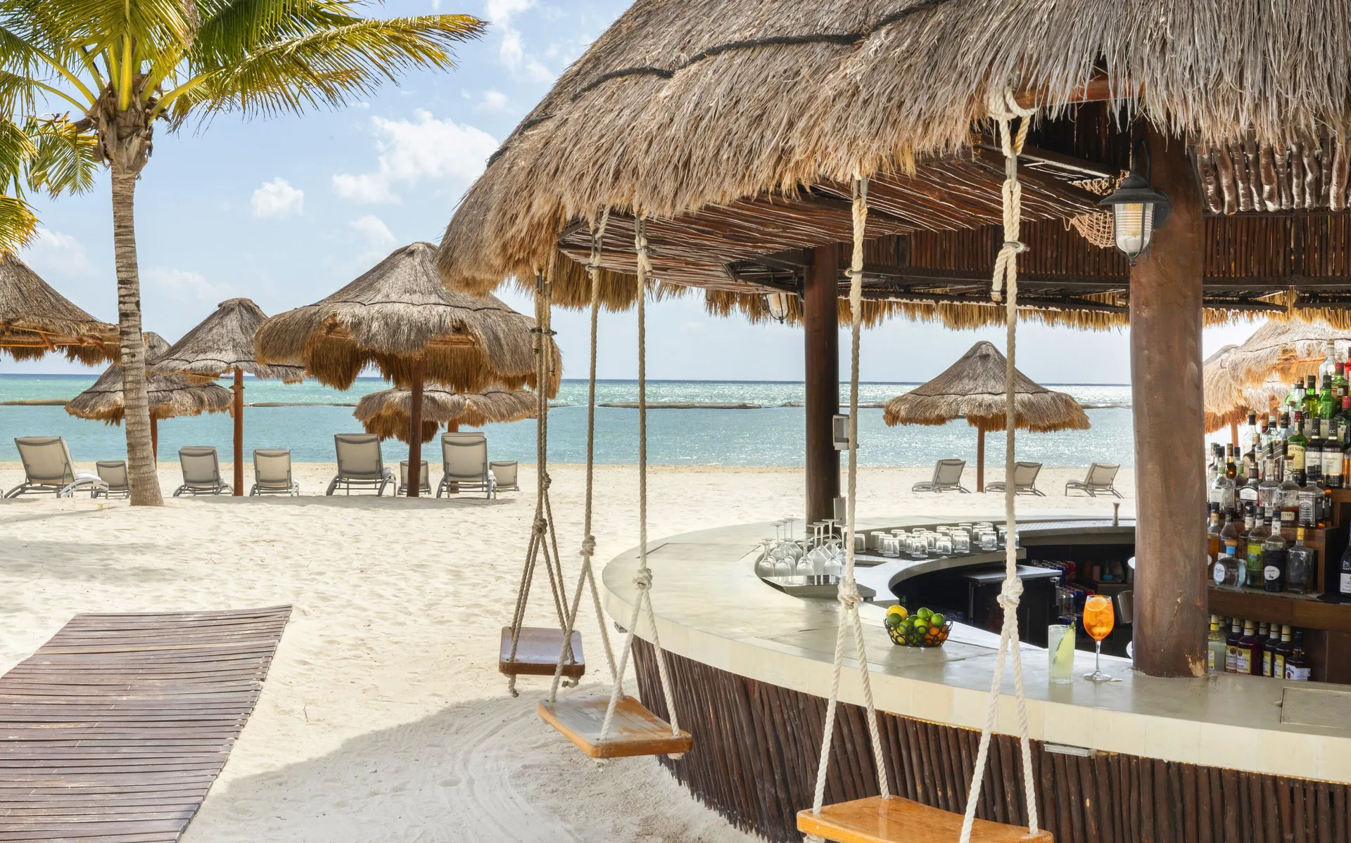 Beach bar with swing seats and palapa umbrellas at Fairmont Mayakoba.