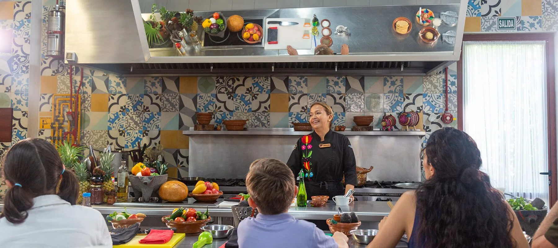 Chef leading a cooking class in a tiled kitchen at Fairmont Mayakoba.