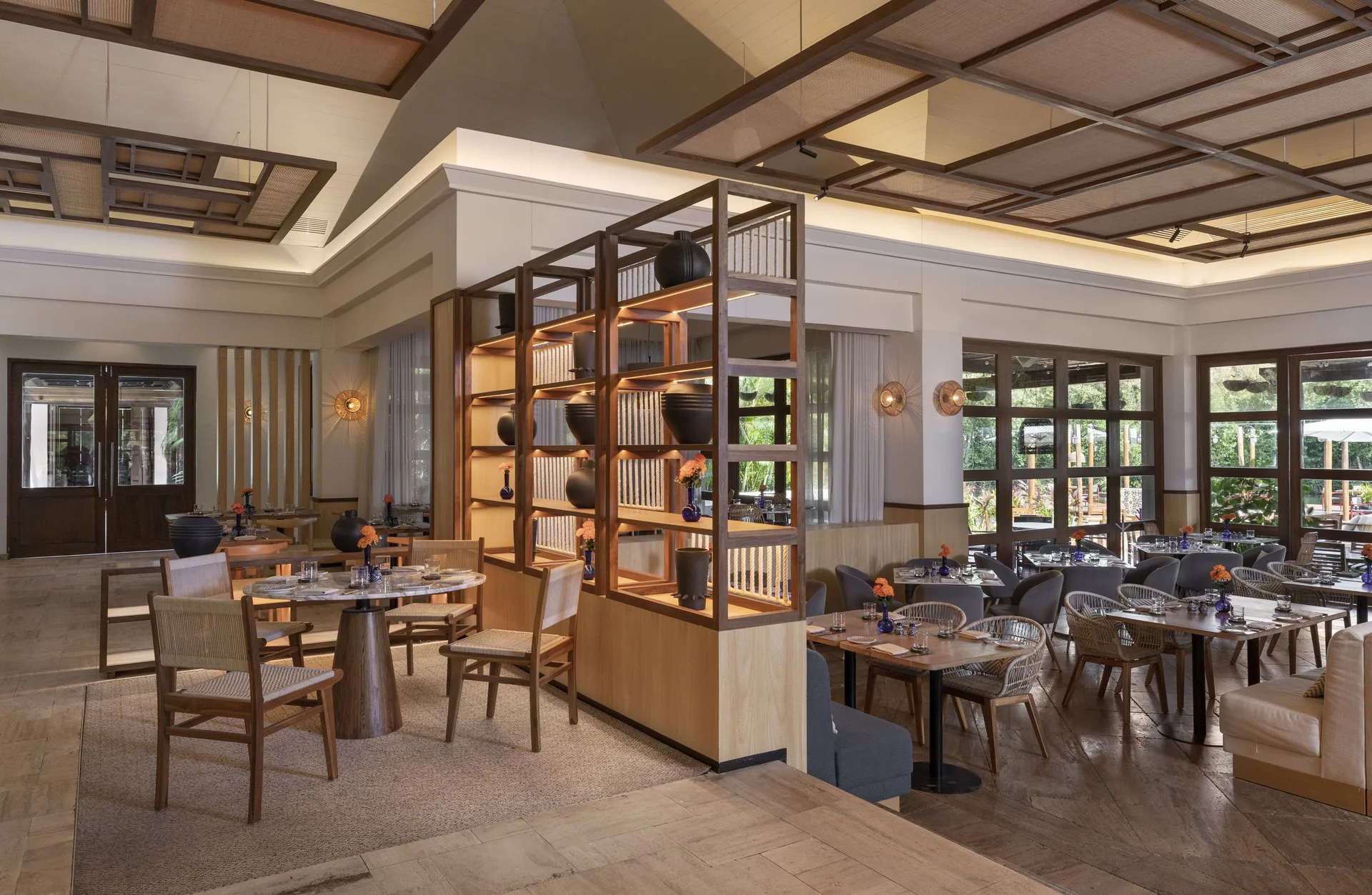 Spacious restaurant dining room with wood shelving and set tables at Fairmont Mayakoba.