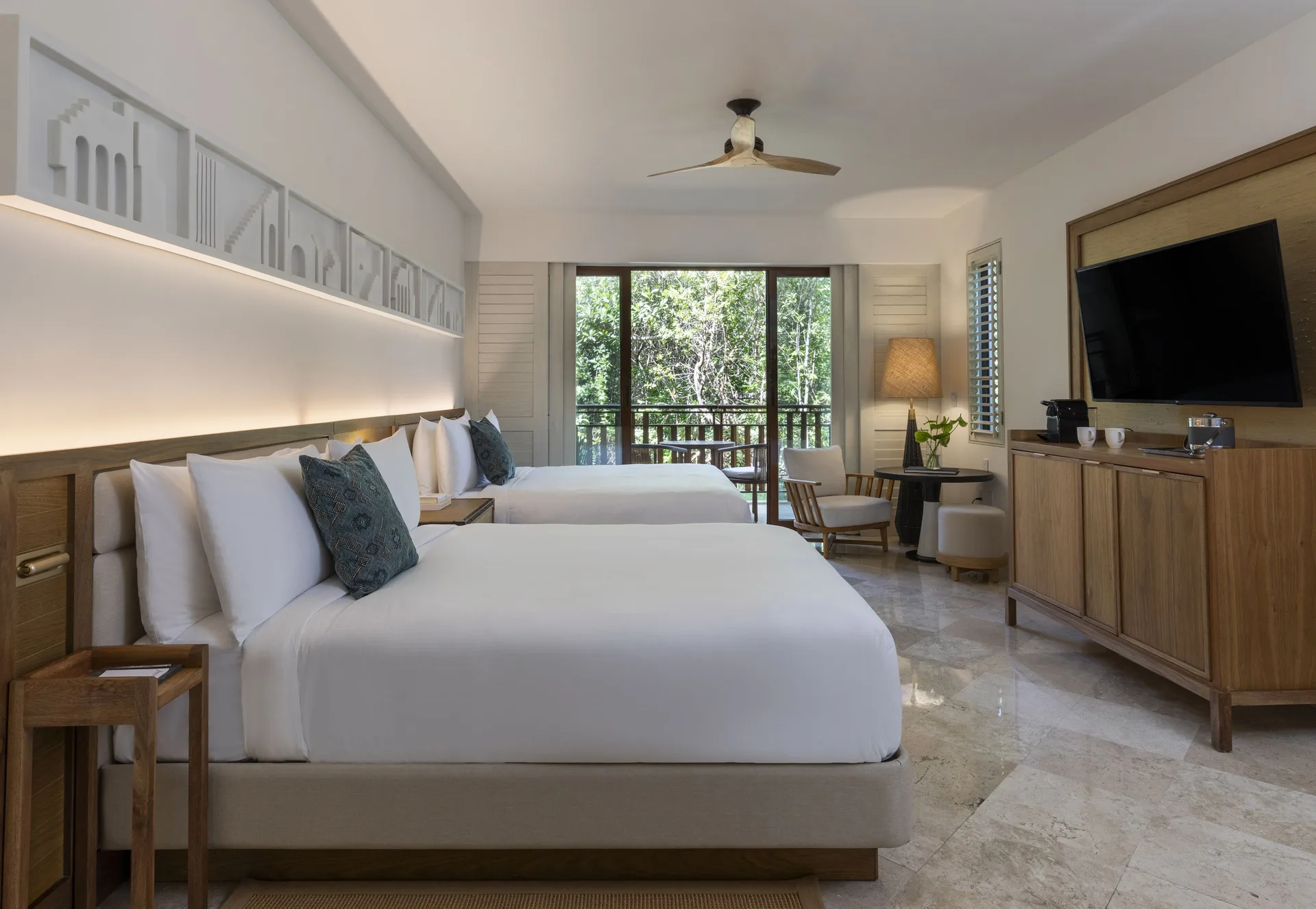 Two double beds in a Casita Deluxe Room at Fairmont Mayakoba with balcony and forest view.