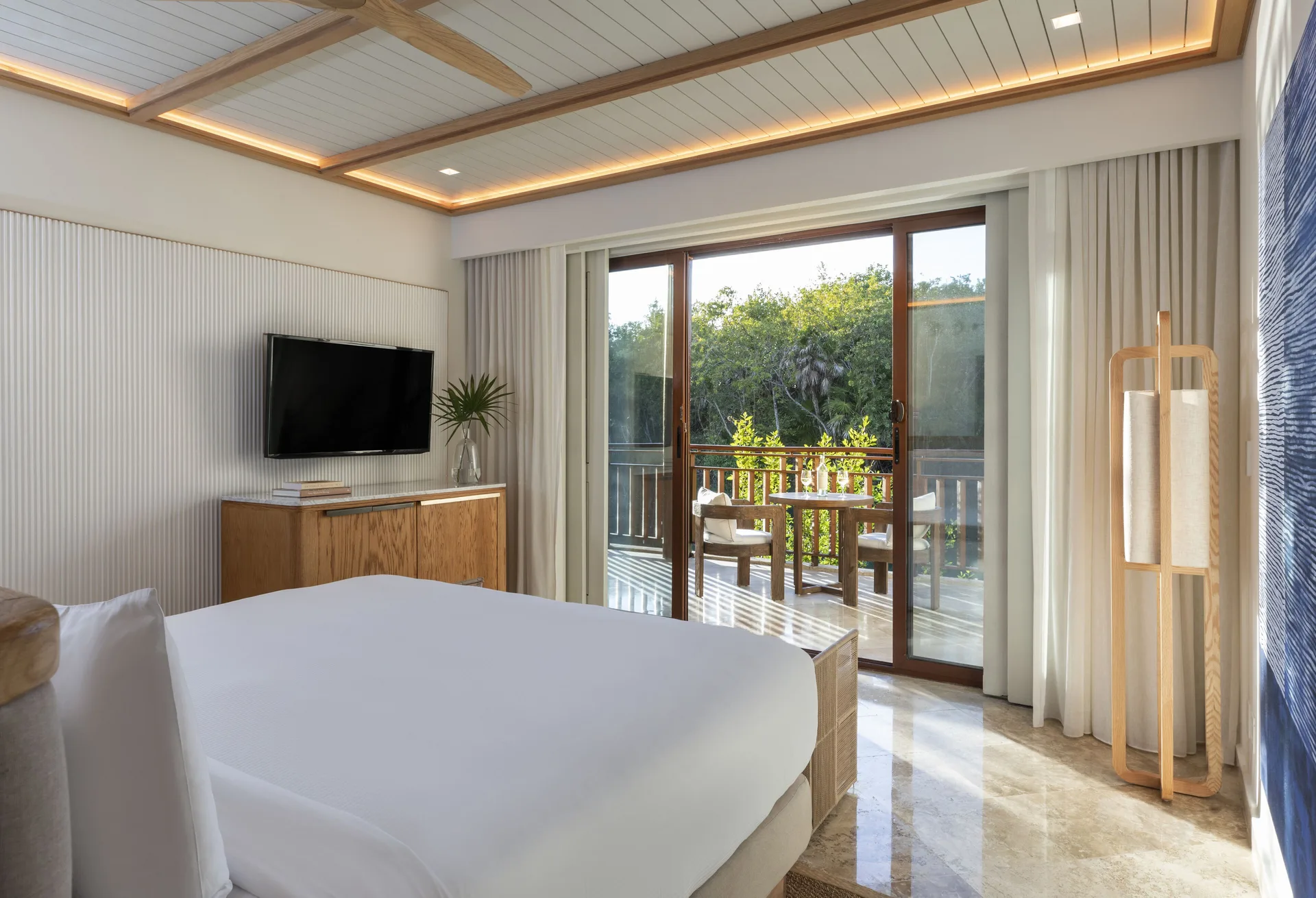 Casita room with a bed, TV, and balcony doors facing greenery at Fairmont Mayakoba.