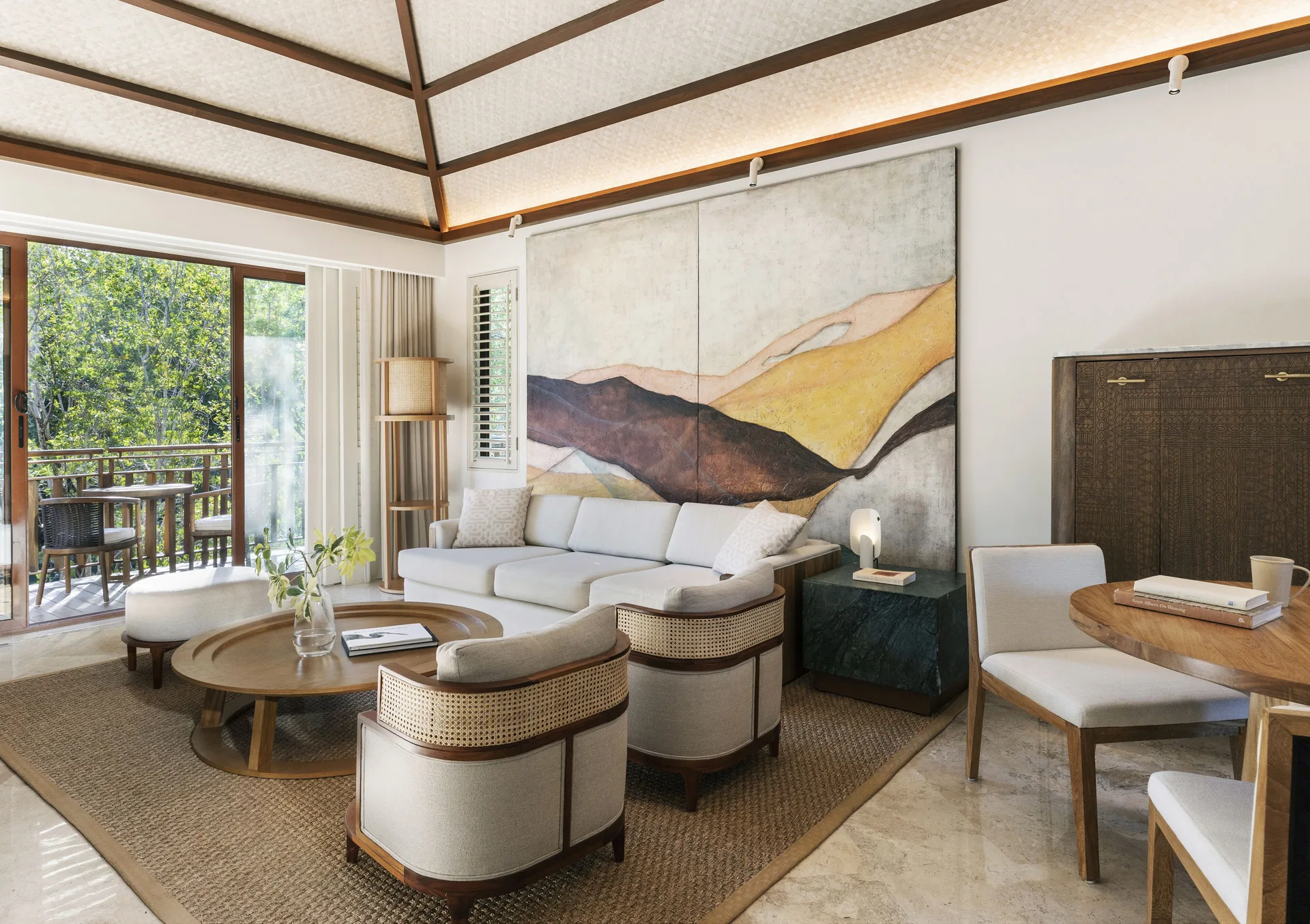 Living room with sofa bed and balcony in a canal-view suite at Fairmont Mayakoba.