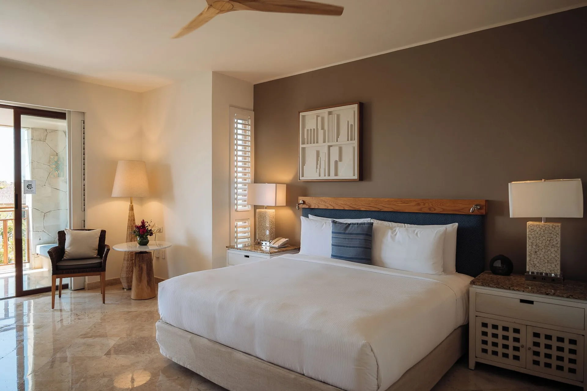 King bed room with balcony door, lamps, and side seating at Fairmont Mayakoba.