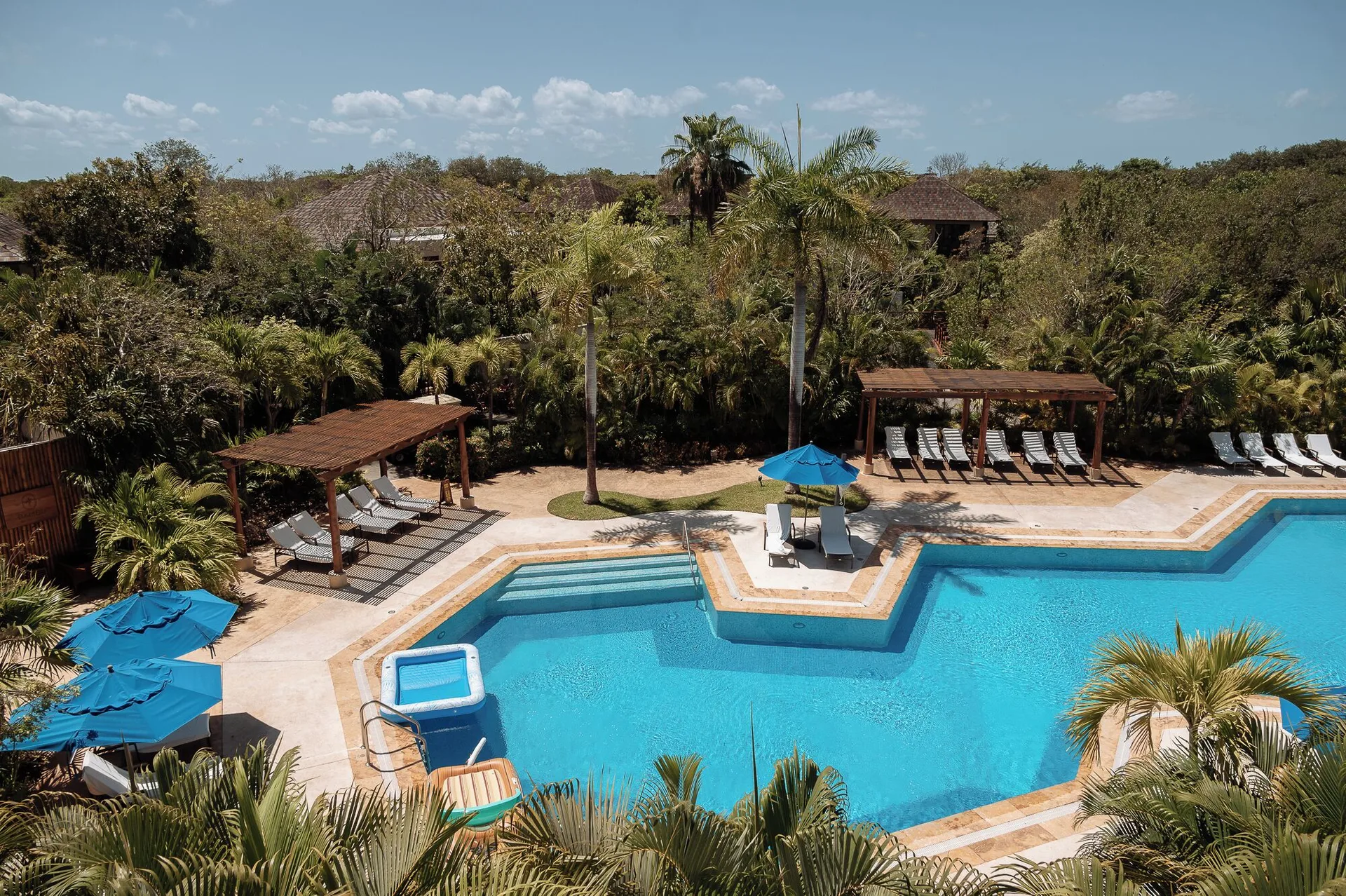 Outdoor pool with blue umbrellas and lounge chairs at Fairmont Mayakoba.