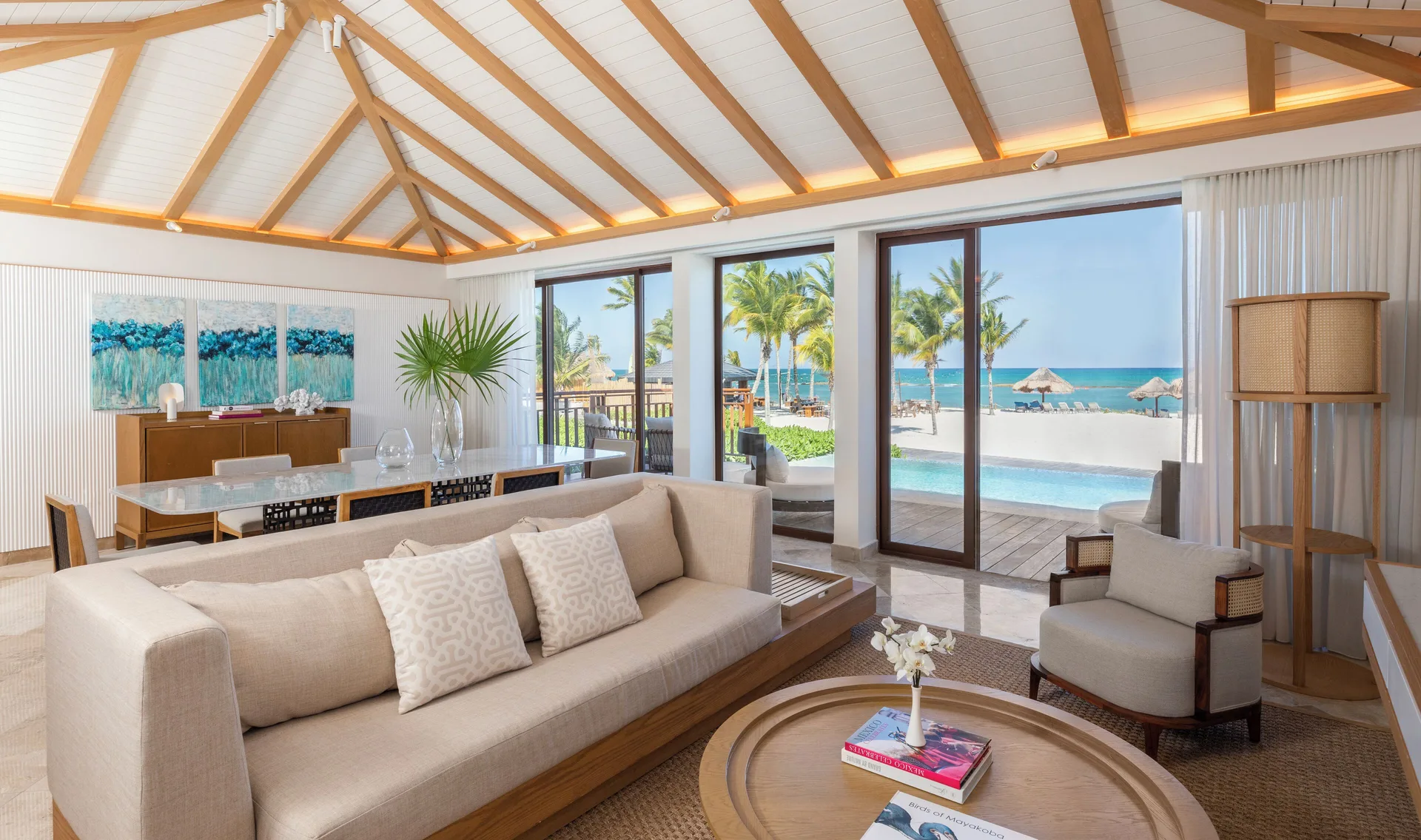 Beachfront premium suite living room with sofa and sea-facing glass doors at Fairmont Mayakoba.