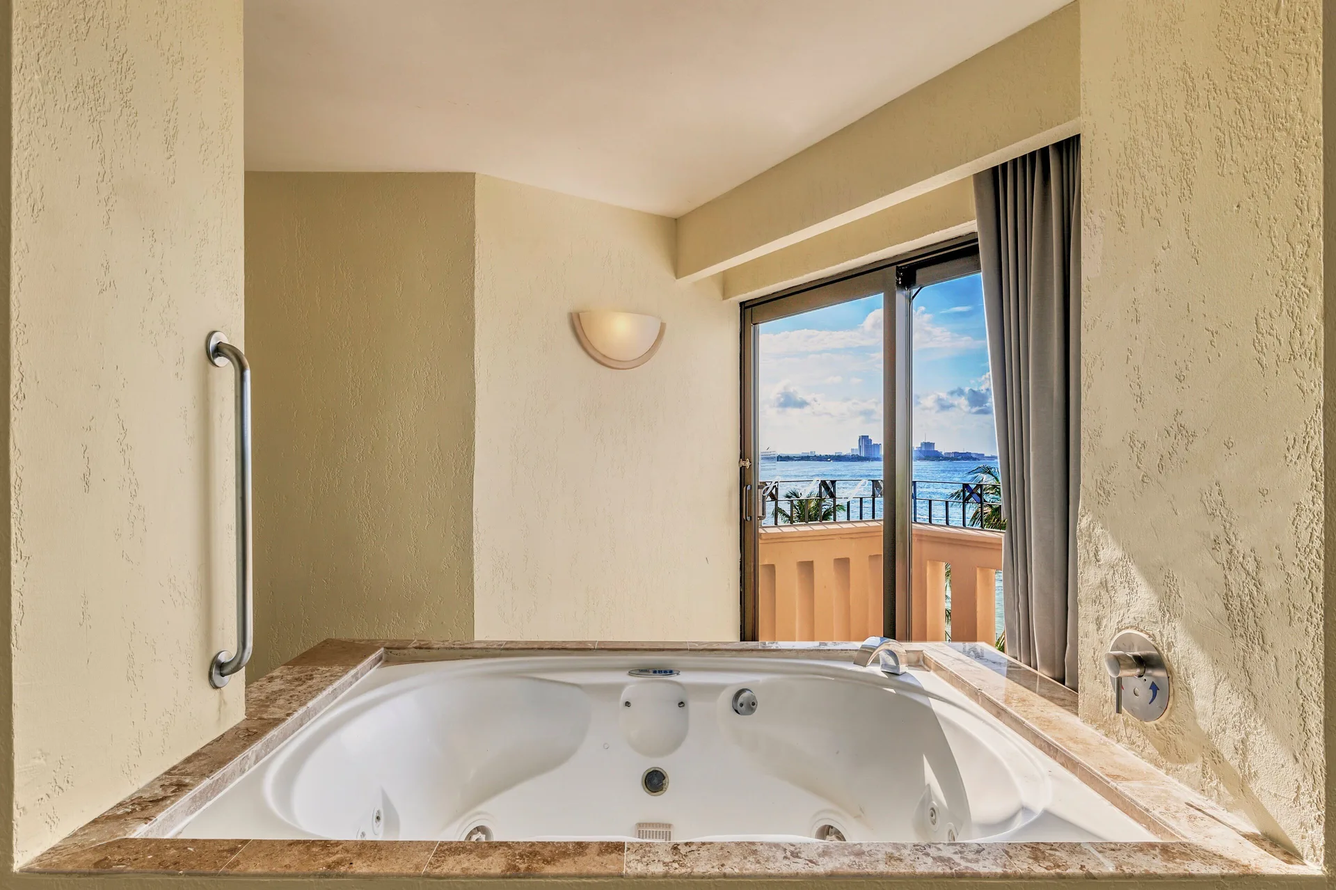 In-room jetted tub with balcony and water view at Fiesta Americana Cancun Villas.