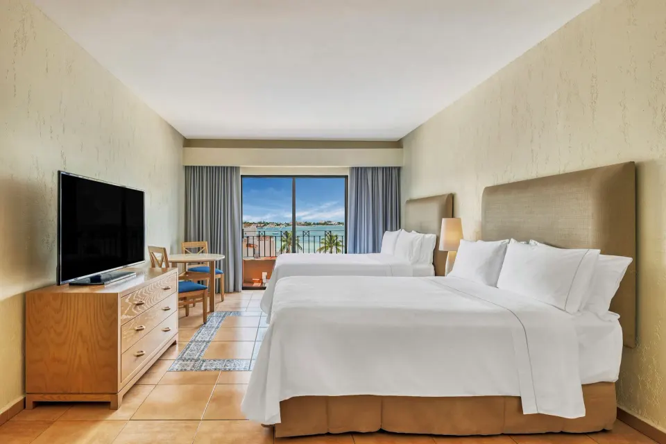 Deluxe Villa with two beds, TV, and balcony view at Fiesta Americana Cancun Villas.