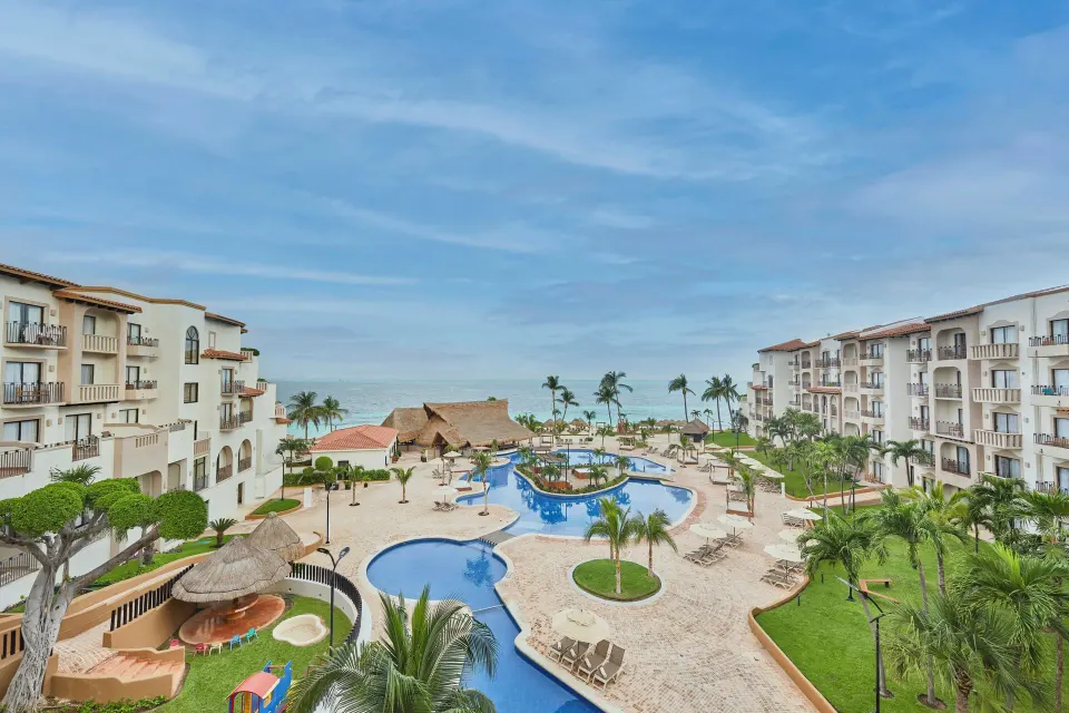 Villa Master Suite balcony view at Fiesta Americana Cancun Villas with pools, palms, and ocean beyond.