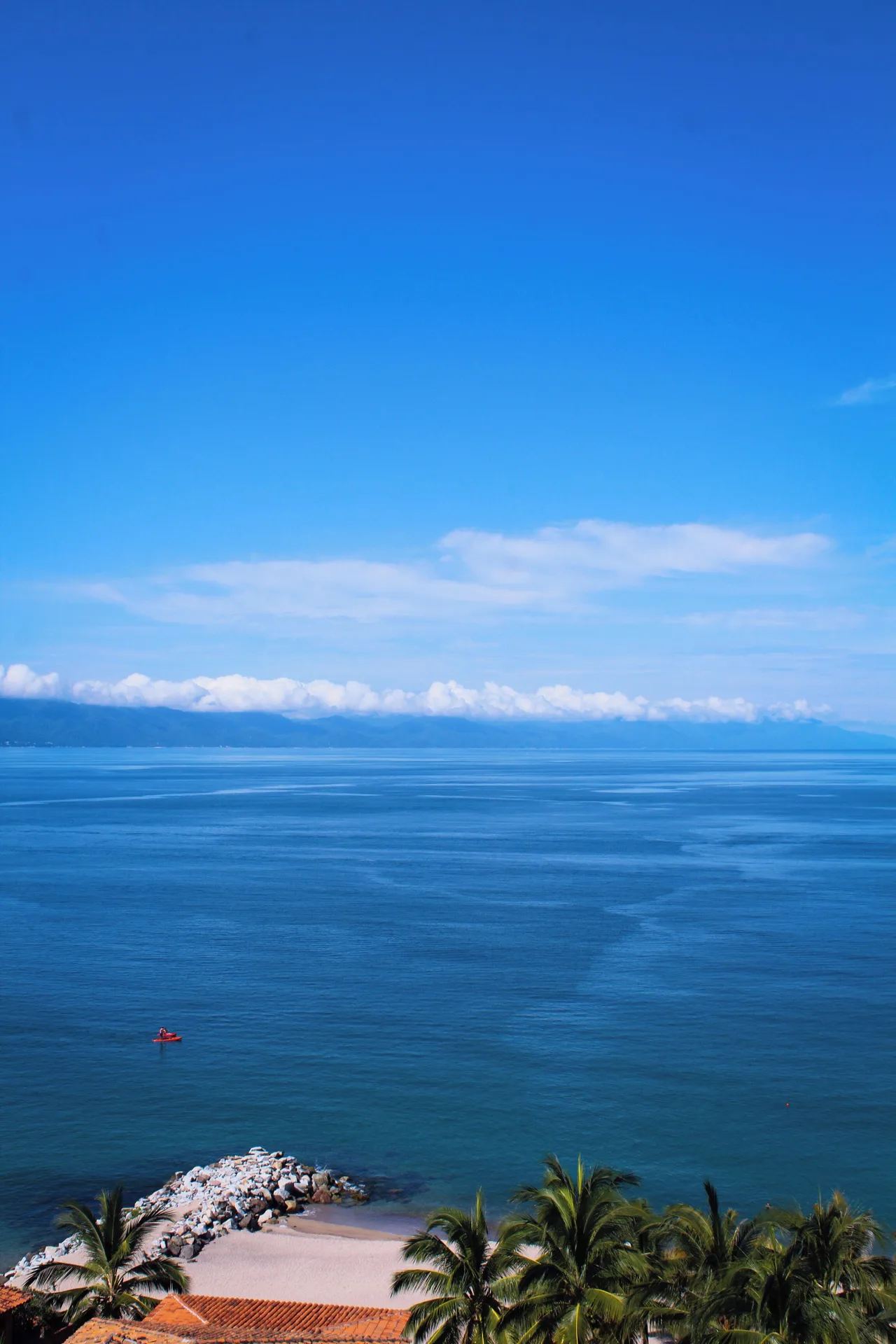 Bay view with blue water, palms, beach, and a small boat at Fiesta Americana Puerto Vallarta & Spa.