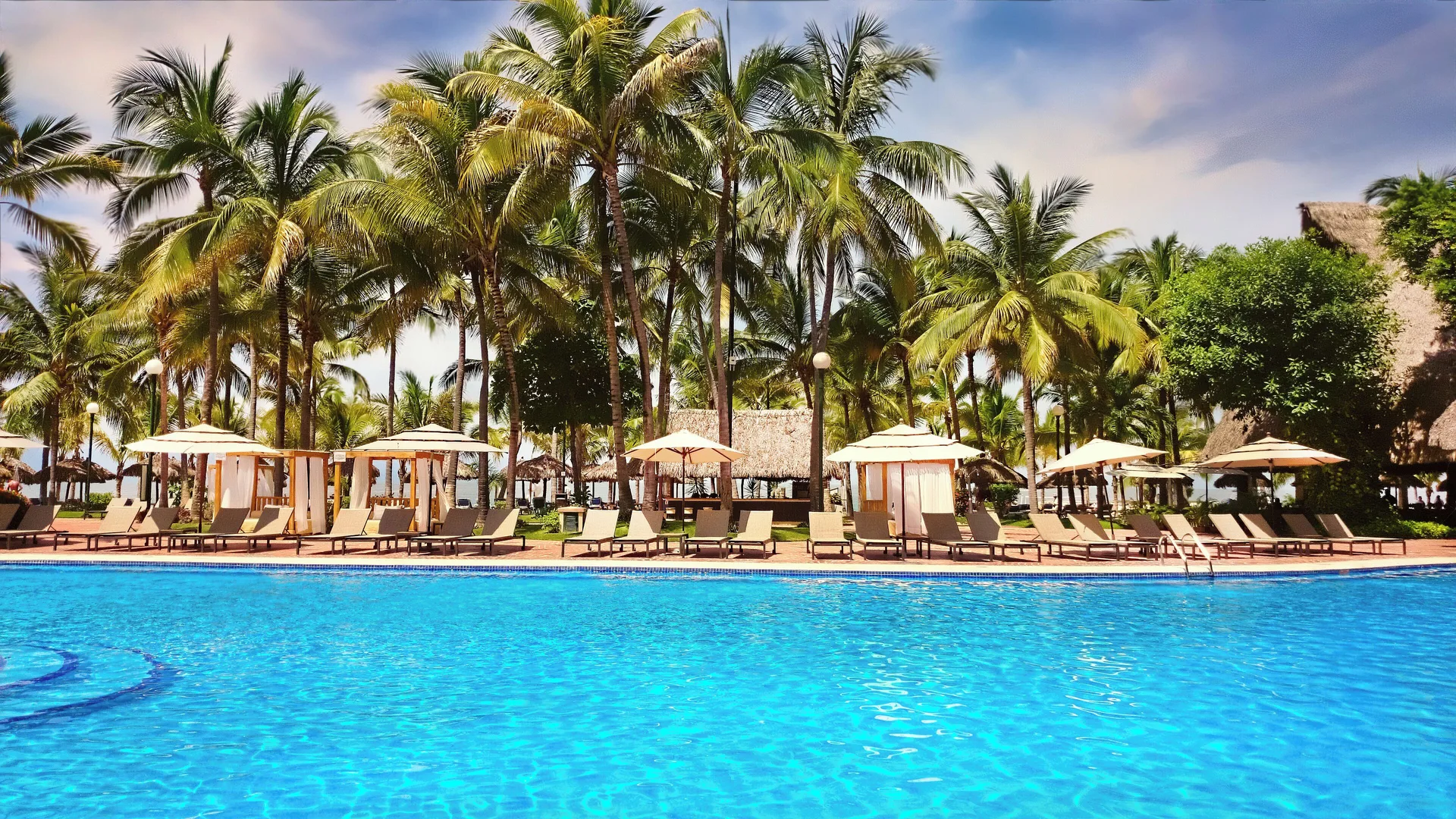 Main pool lined with loungers, cabanas, and palm trees at Fiesta Americana Puerto Vallarta & Spa.