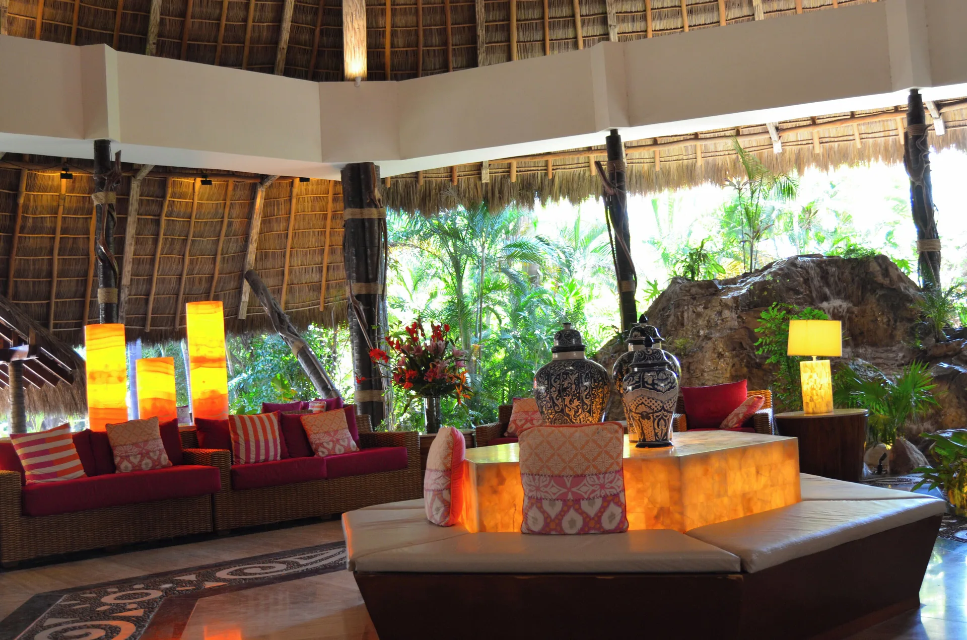 Thatched-roof lobby seating area with red cushions at Fiesta Americana Puerto Vallarta & Spa.