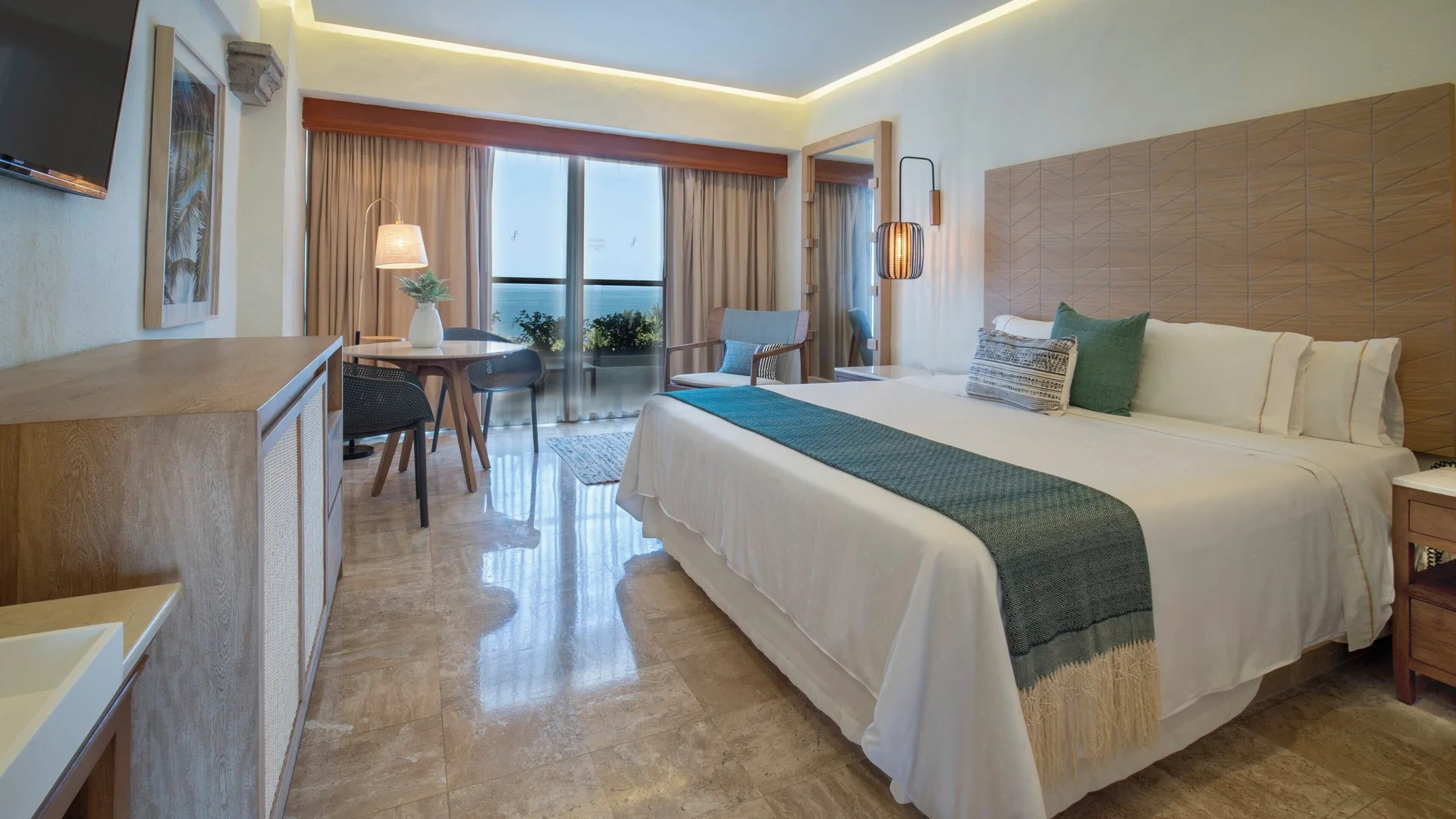 Honeymoon Suite king bed with dining table and balcony doors at Fiesta Americana Puerto Vallarta & Spa.