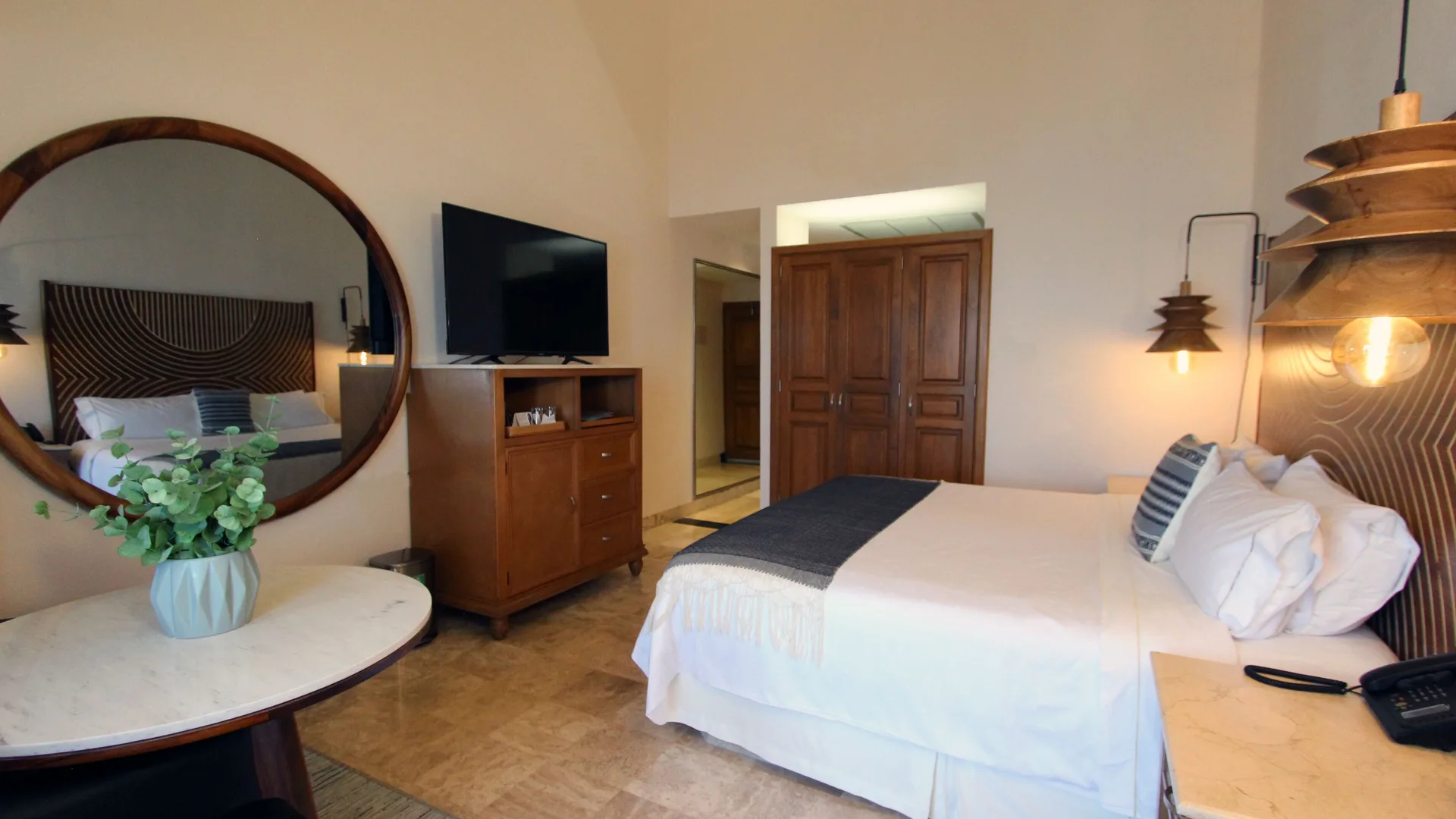 Honeymoon Suite king bed, round mirror, and TV at Fiesta Americana Puerto Vallarta & Spa.