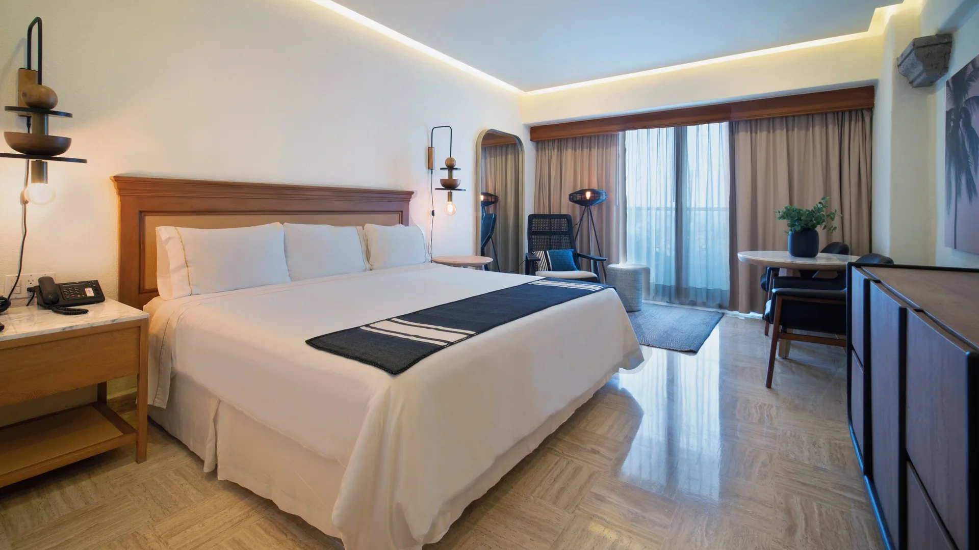 Superior Room king bed at Fiesta Americana Puerto Vallarta & Spa with sitting area and balcony doors.