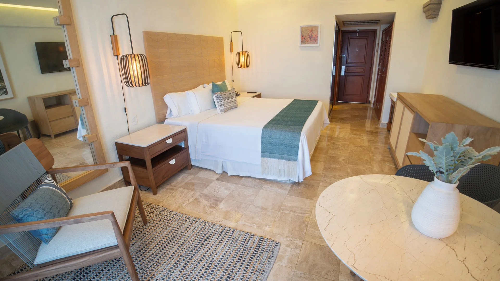 Superior Room king bed at Fiesta Americana Puerto Vallarta & Spa with chair, table, dresser, and entry door.
