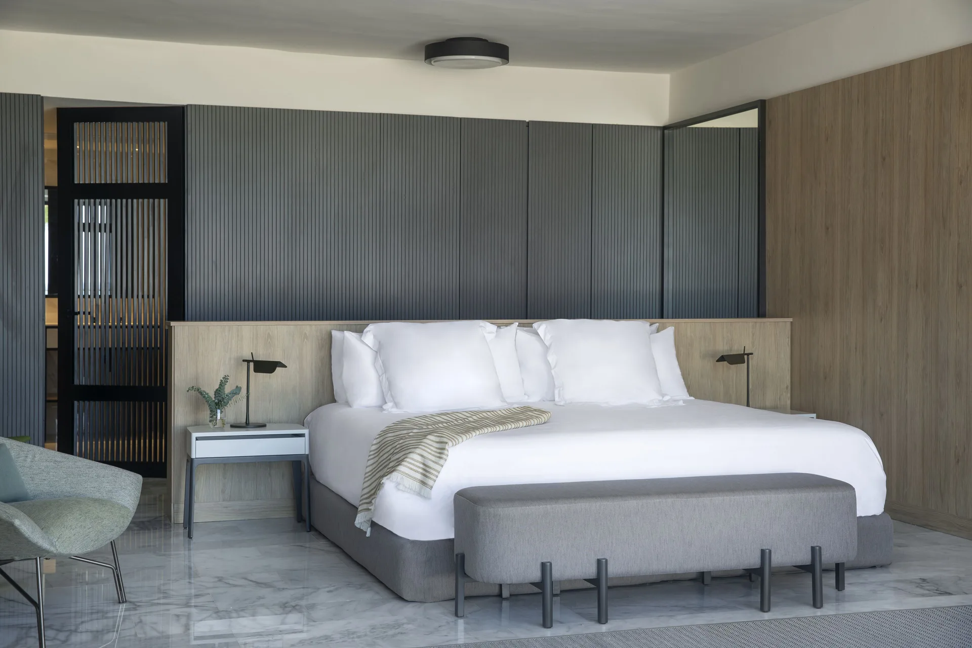 Guest room with a king bed, bench, and wood-paneled walls at Finest Punta Cana.