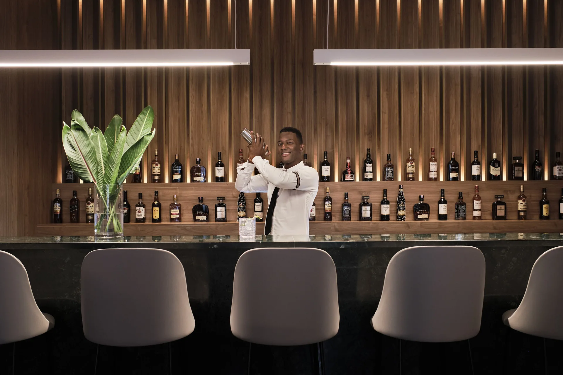 Bartender behind a marble bar with bottle shelves at Finest Punta Cana.