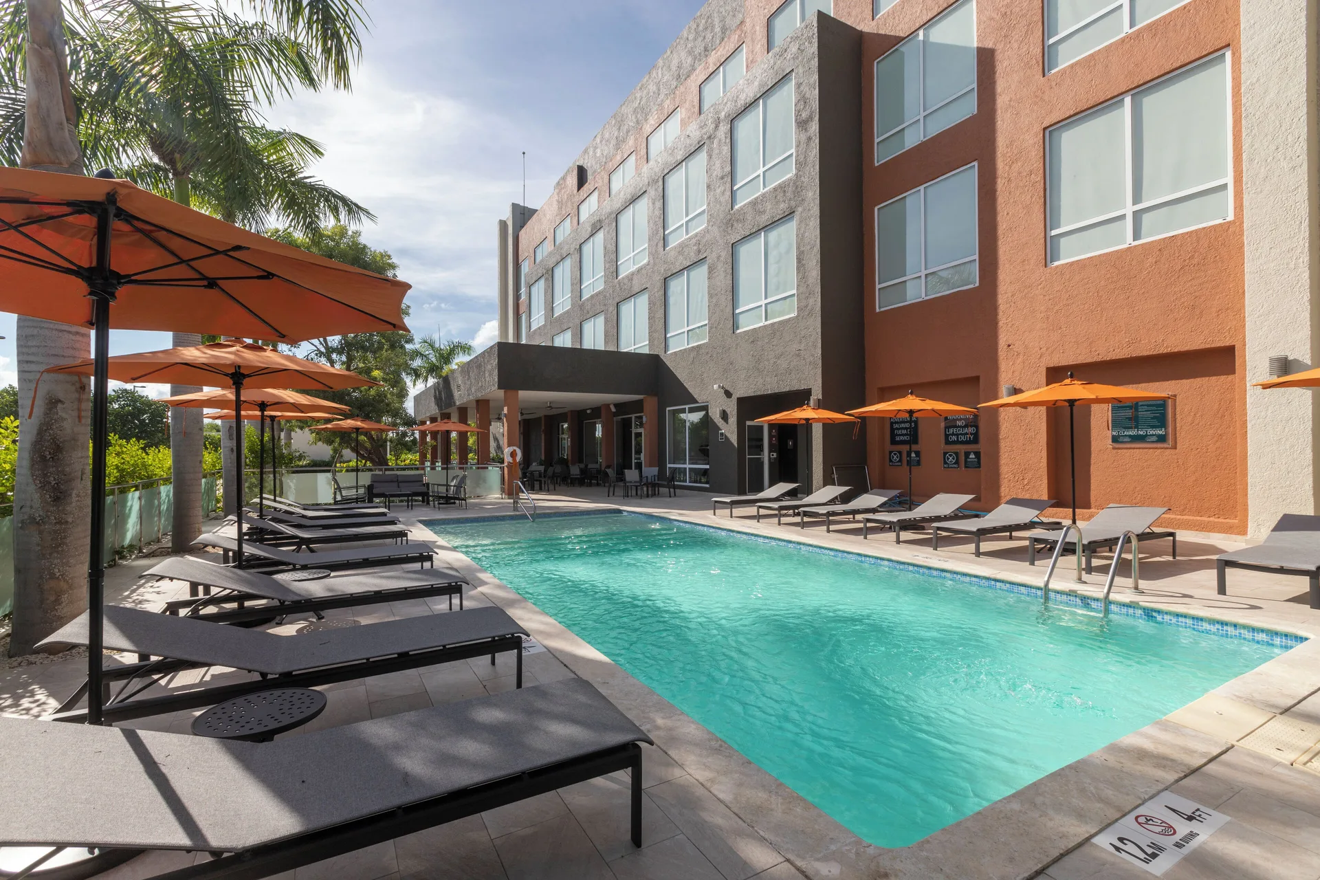 Outdoor pool with loungers and orange umbrellas at Four Points Puntacana Village.