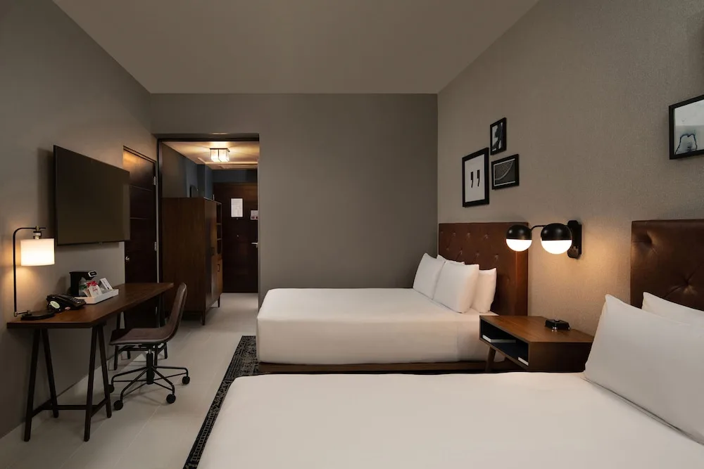 Traditional room with two beds, desk and wall-mounted TV at Four Points Puntacana Village.