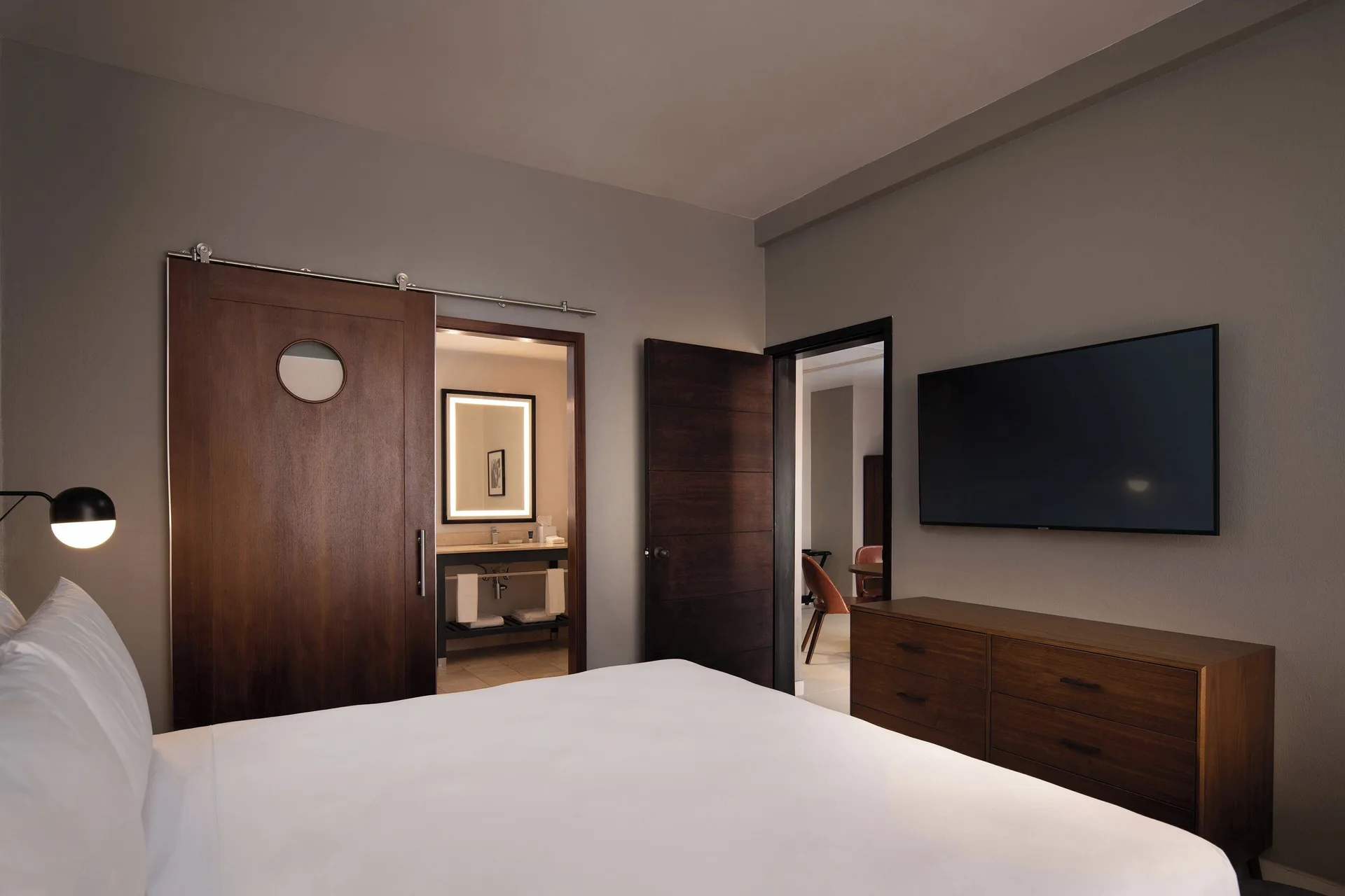 One-bedroom suite king bed with bathroom entry and TV at Four Points Puntacana Village.