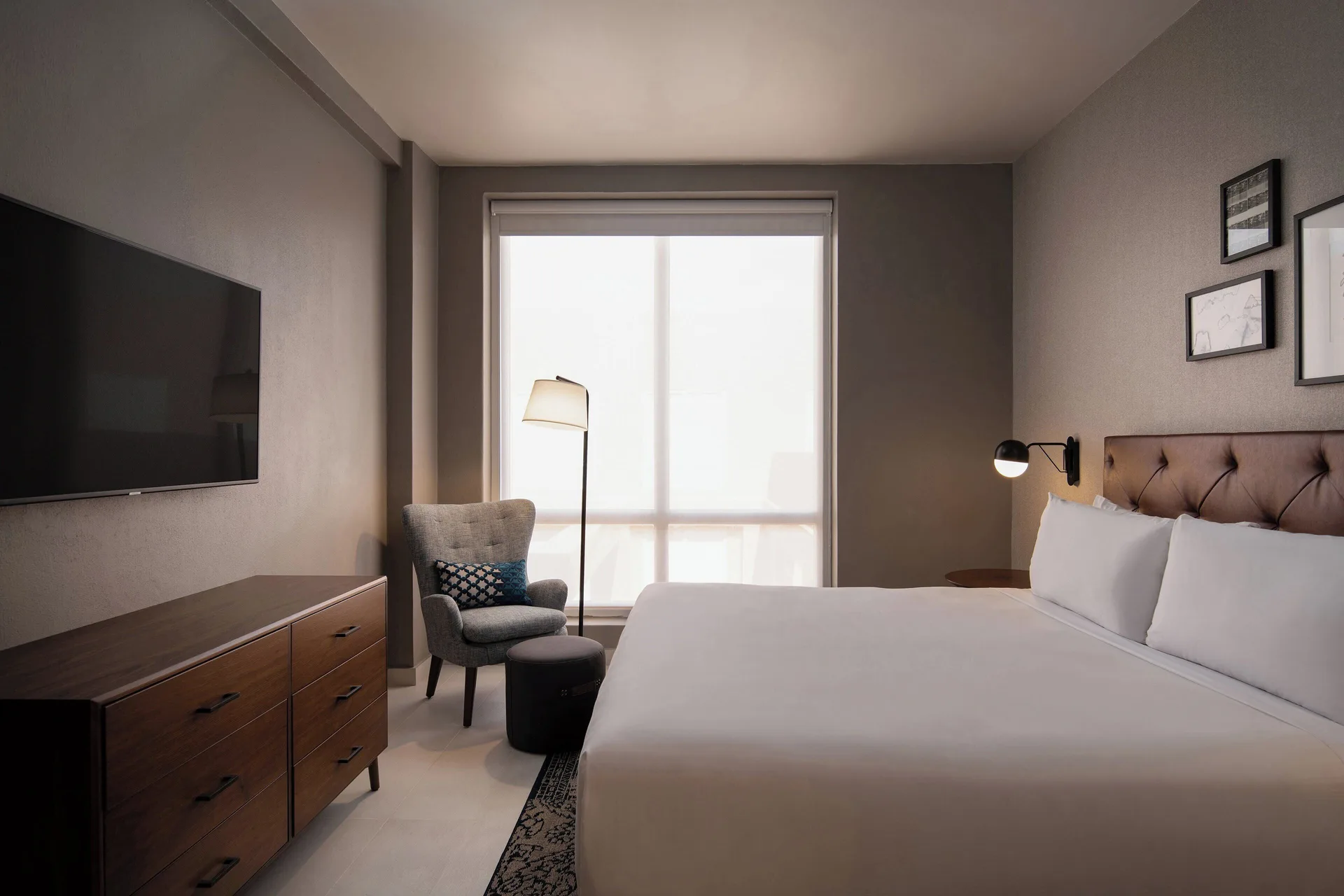 One-bedroom suite king bed with TV and armchair at Four Points Puntacana Village.