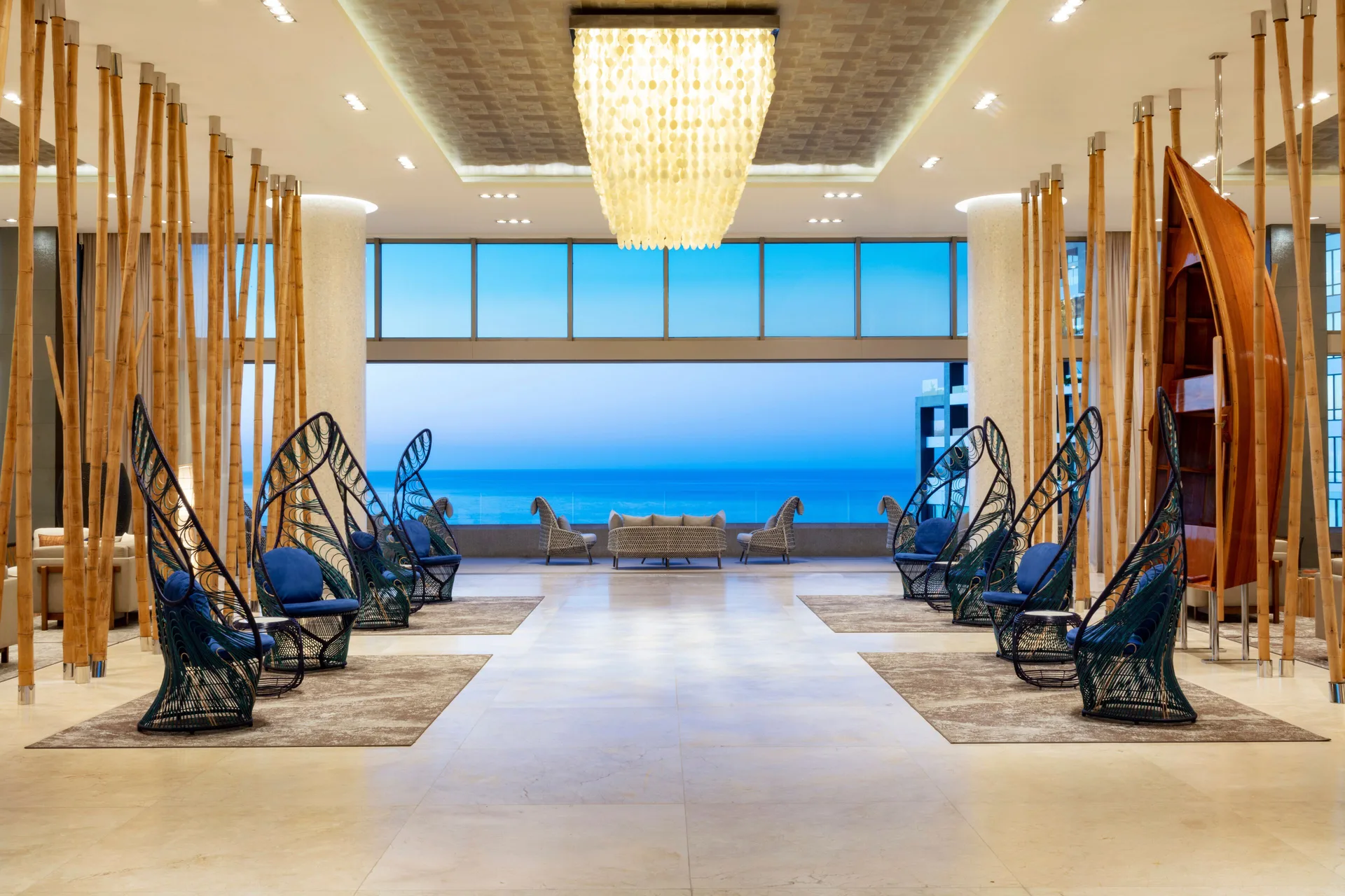Lobby lounge with blue peacock-style chairs and ocean view at Garza Blanca Los Cabos.