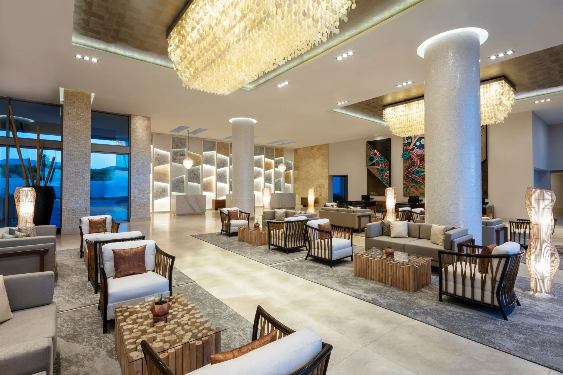 Evening lobby lounge with sofas and glowing chandeliers at Garza Blanca Los Cabos.