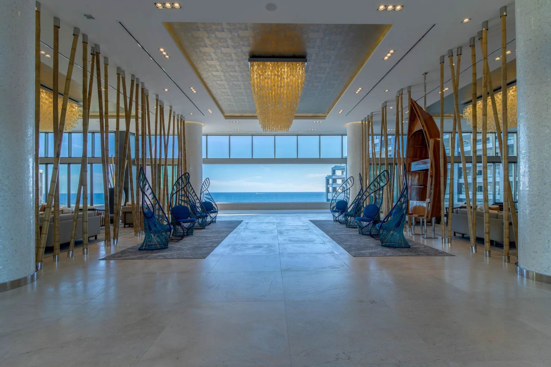 Ocean-facing lobby lounge with blue woven chairs at Garza Blanca Los Cabos.