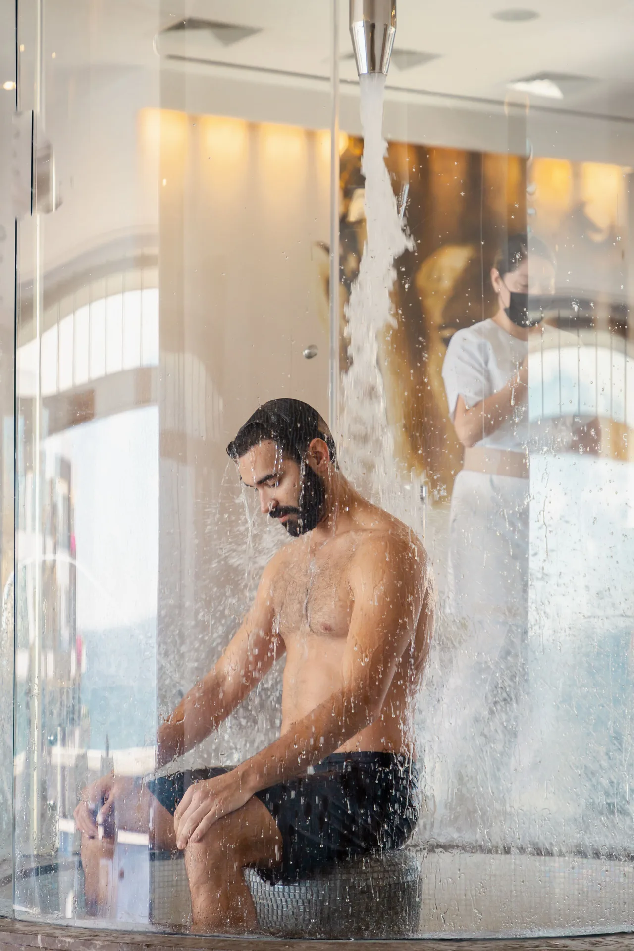 Guest sits beneath a water feature in the spa at Garza Blanca Los Cabos.
