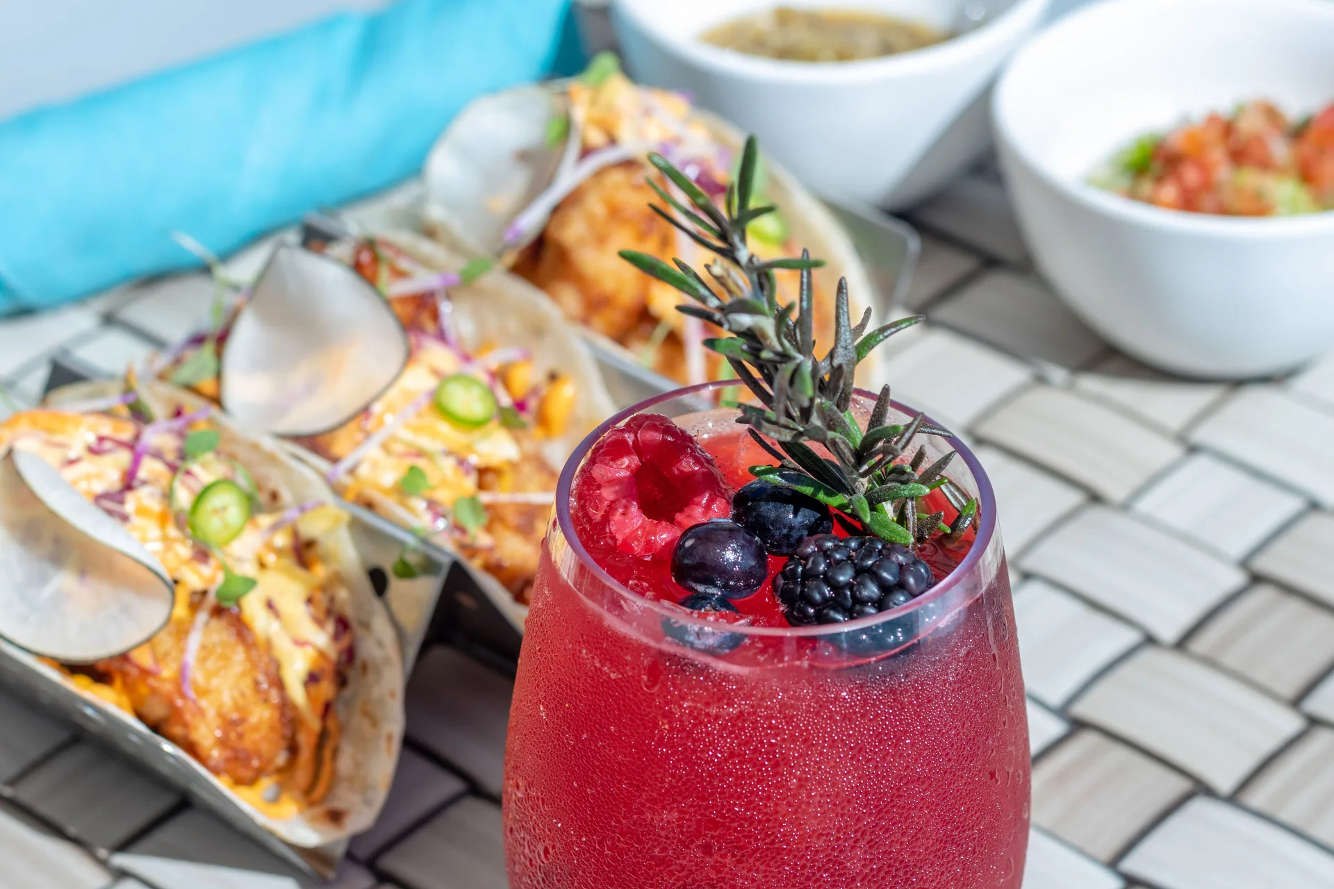 Red berry cocktail with tacos and small bowls on a table at Garza Blanca Los Cabos.