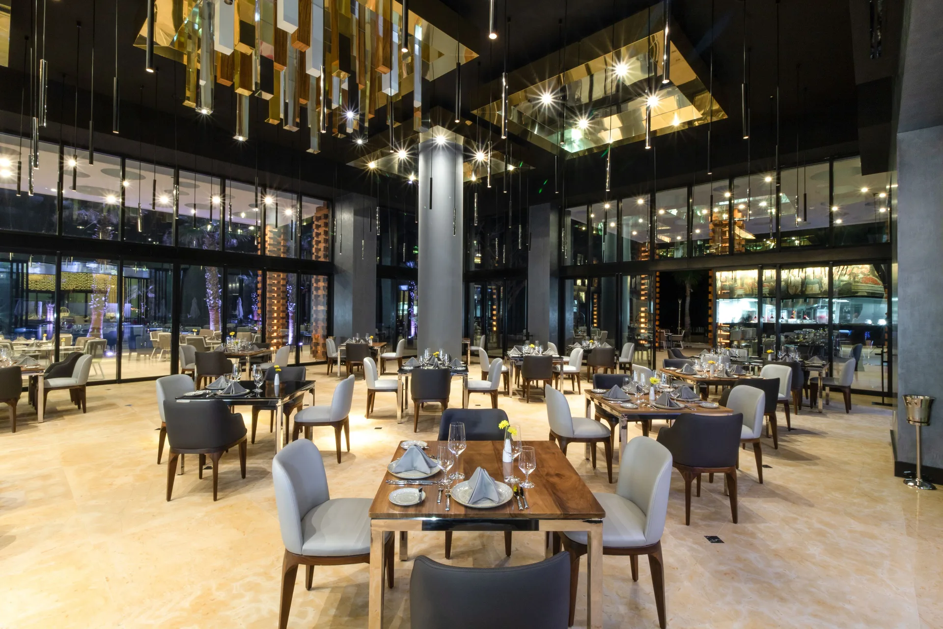 Contemporary dining room with set tables and chandeliers at Garza Blanca Los Cabos.