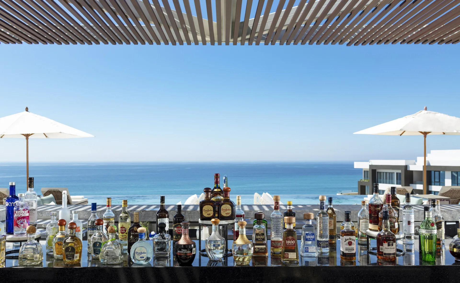 Rooftop bar counter with bottles overlooking the ocean at Garza Blanca Los Cabos.