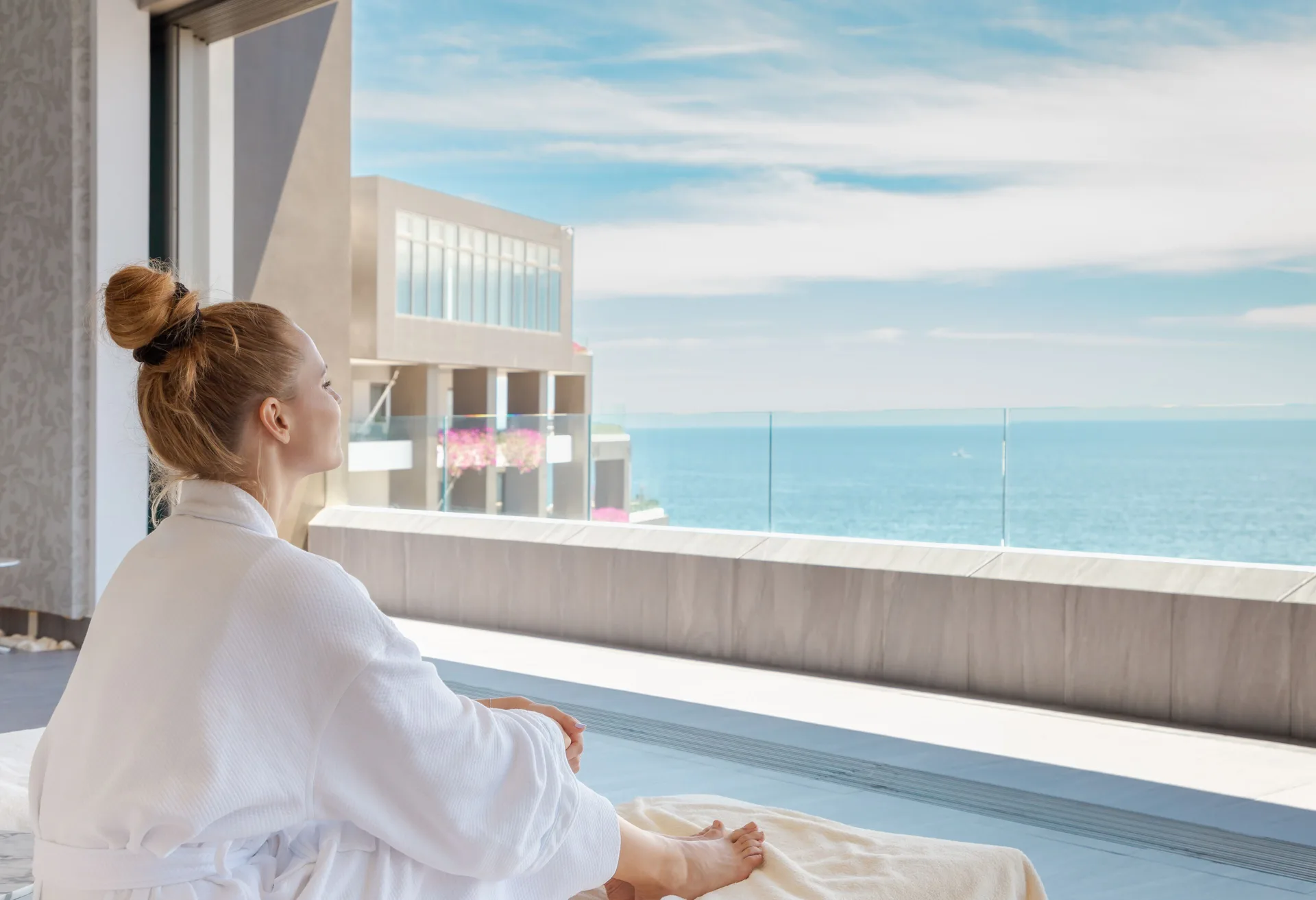 Robe-clad guest seated by an ocean-view balcony at Garza Blanca Los Cabos.