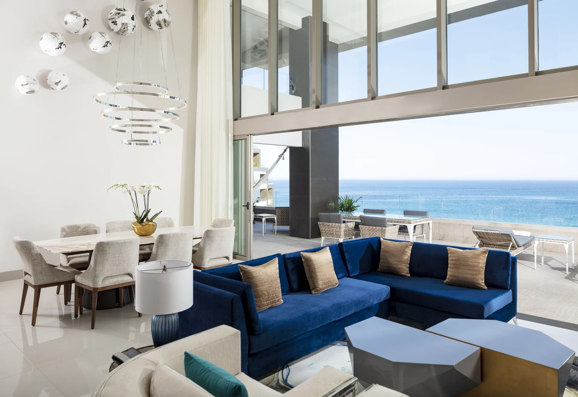 Ocean-view living room with blue sectional and terrace access at Garza Blanca Los Cabos.