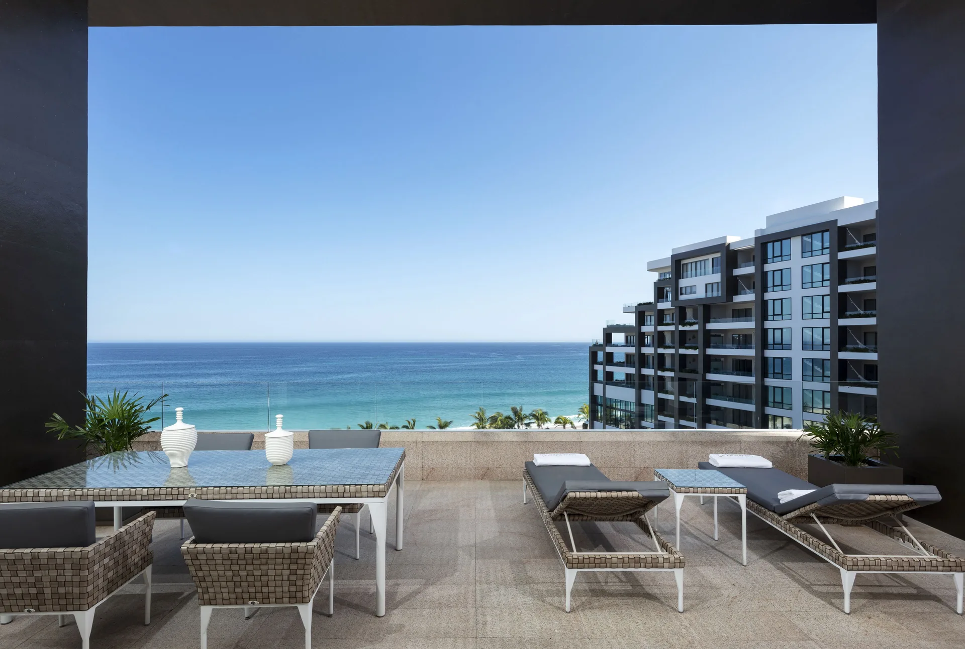 Private terrace with loungers, dining table, and ocean view at Garza Blanca Los Cabos.