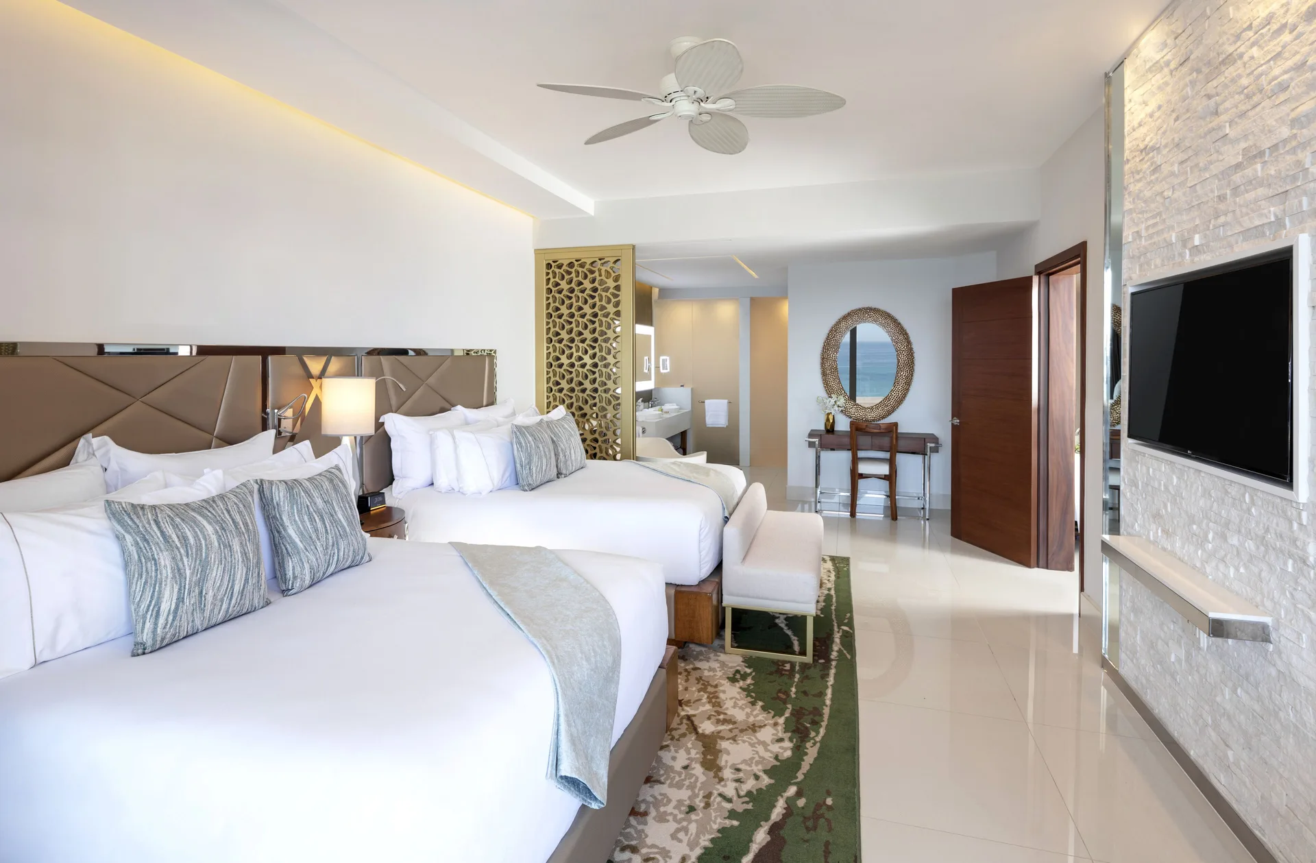 Two-bed guest room with TV wall and vanity area at Garza Blanca Los Cabos.