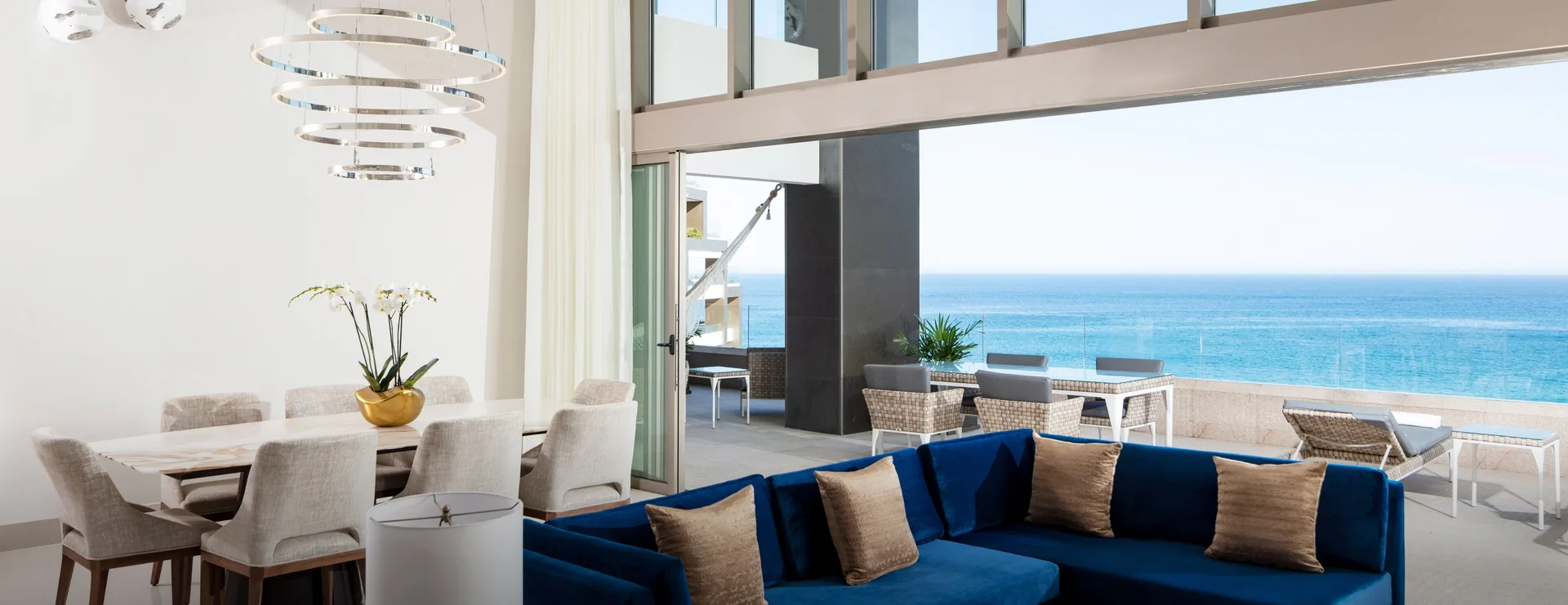 Penthouse living room and dining area at Garza Blanca Los Cabos opening to an oceanfront terrace.