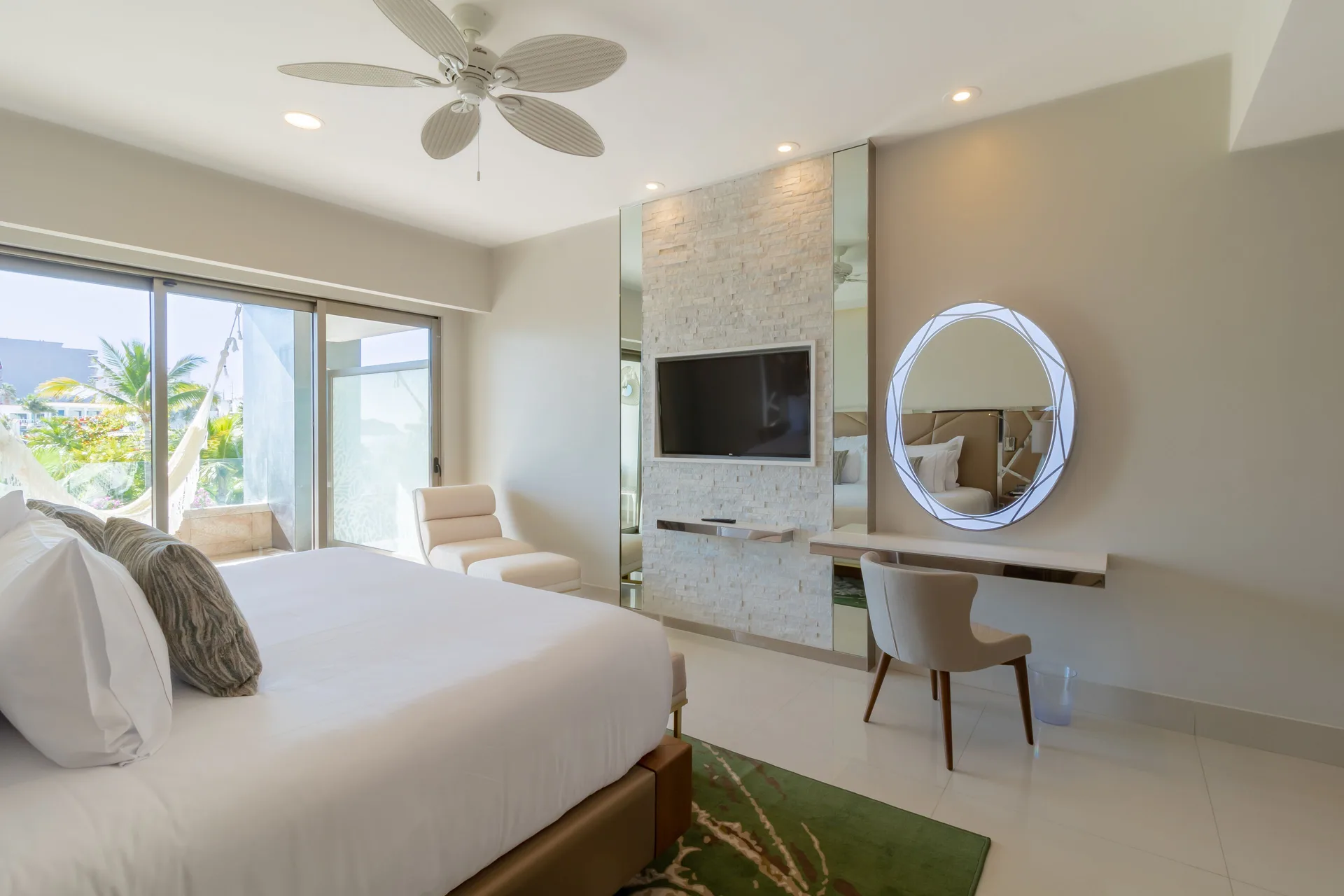 Junior Suite with bed, TV wall, vanity, and balcony hammock view at Garza Blanca Los Cabos.