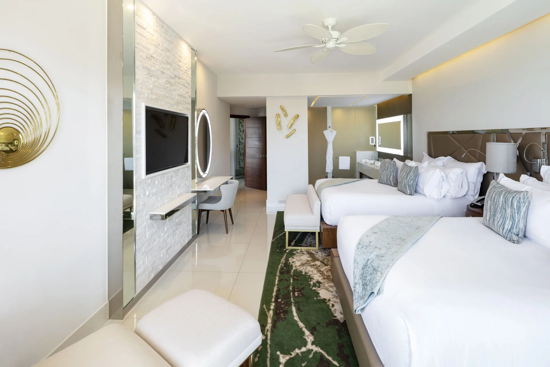 Junior Suite with two beds, TV wall, vanity, and open bathroom area at Garza Blanca Los Cabos.