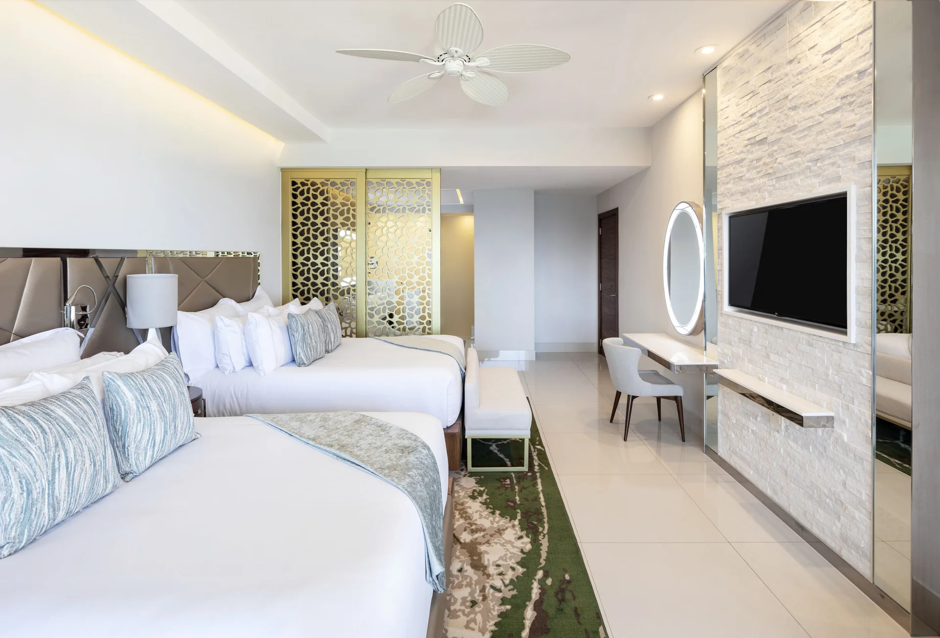 Junior Suite with two beds, patterned divider, vanity desk, and TV wall at Garza Blanca Los Cabos.