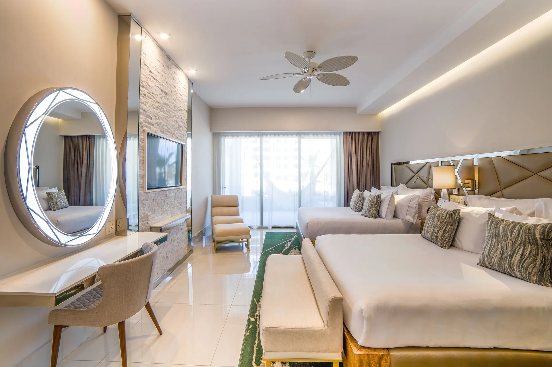 Junior Suite with two beds, vanity, TV wall, and balcony doors at Garza Blanca Los Cabos.